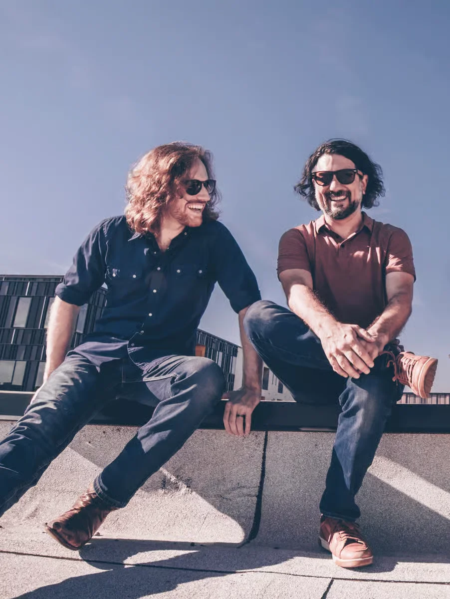 Two men laughing together on a sunny rooftop