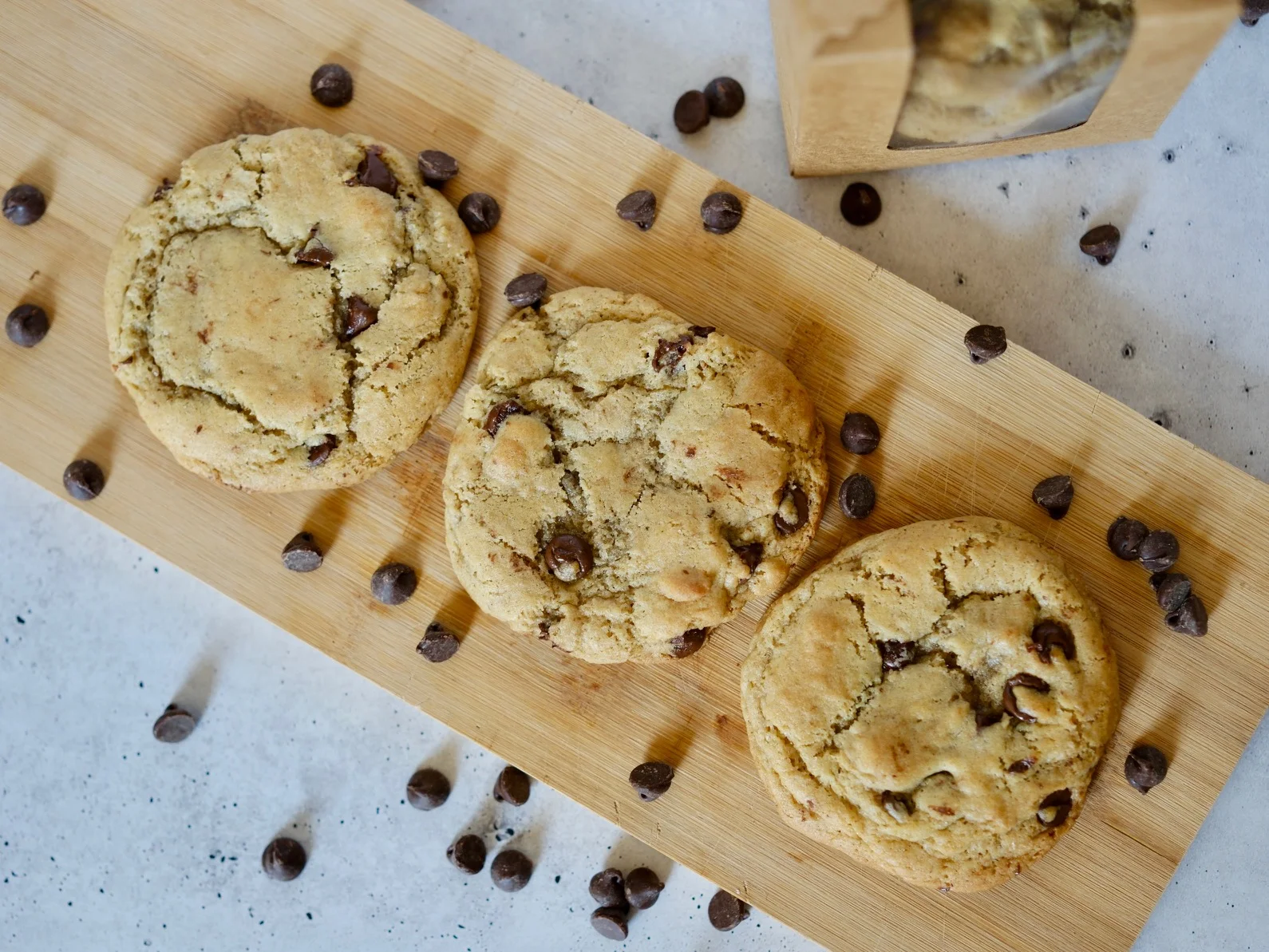 Freshly baked chocolate chip cookies on a wooden board
