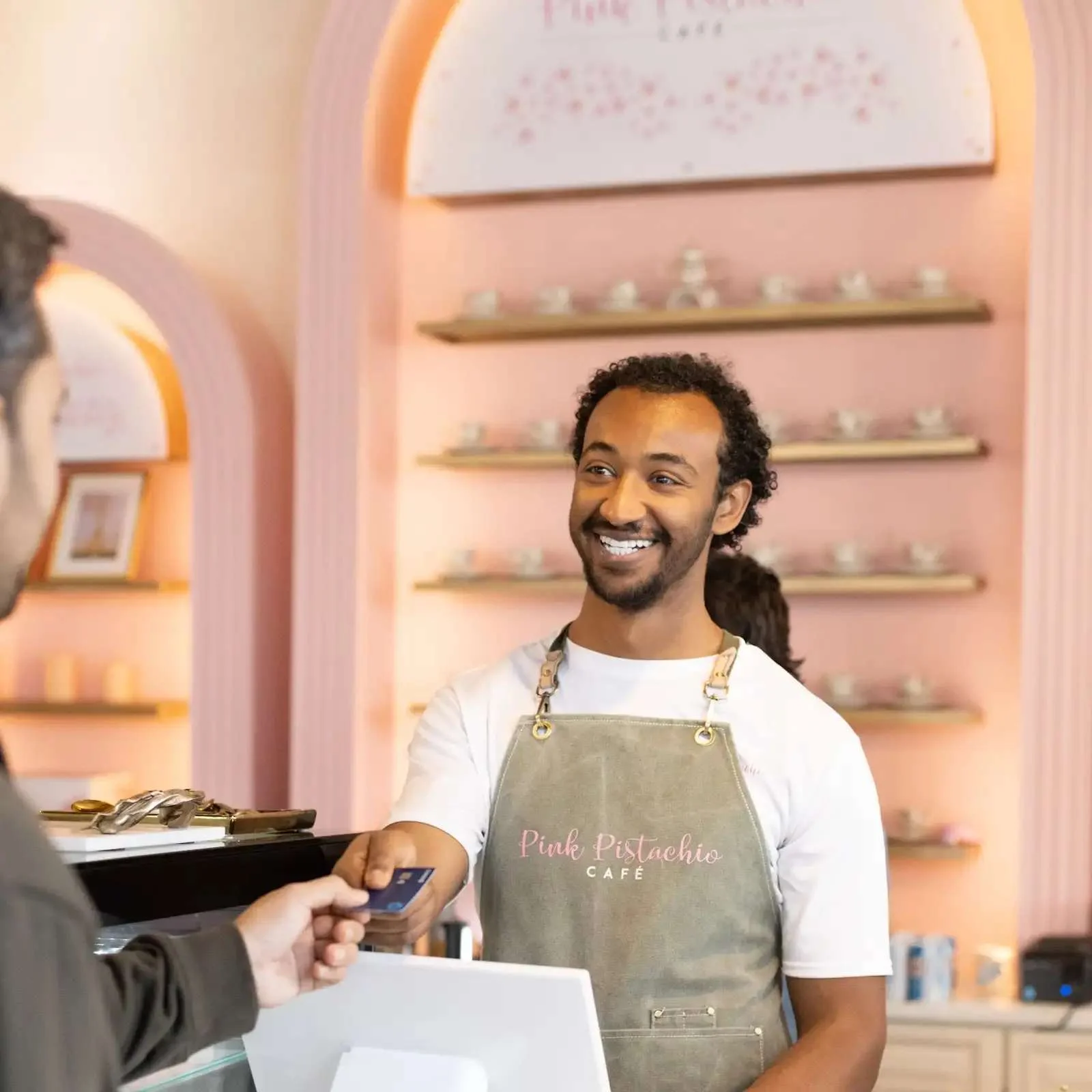 Friendly barista at Pink Pistachio Café serving a customer