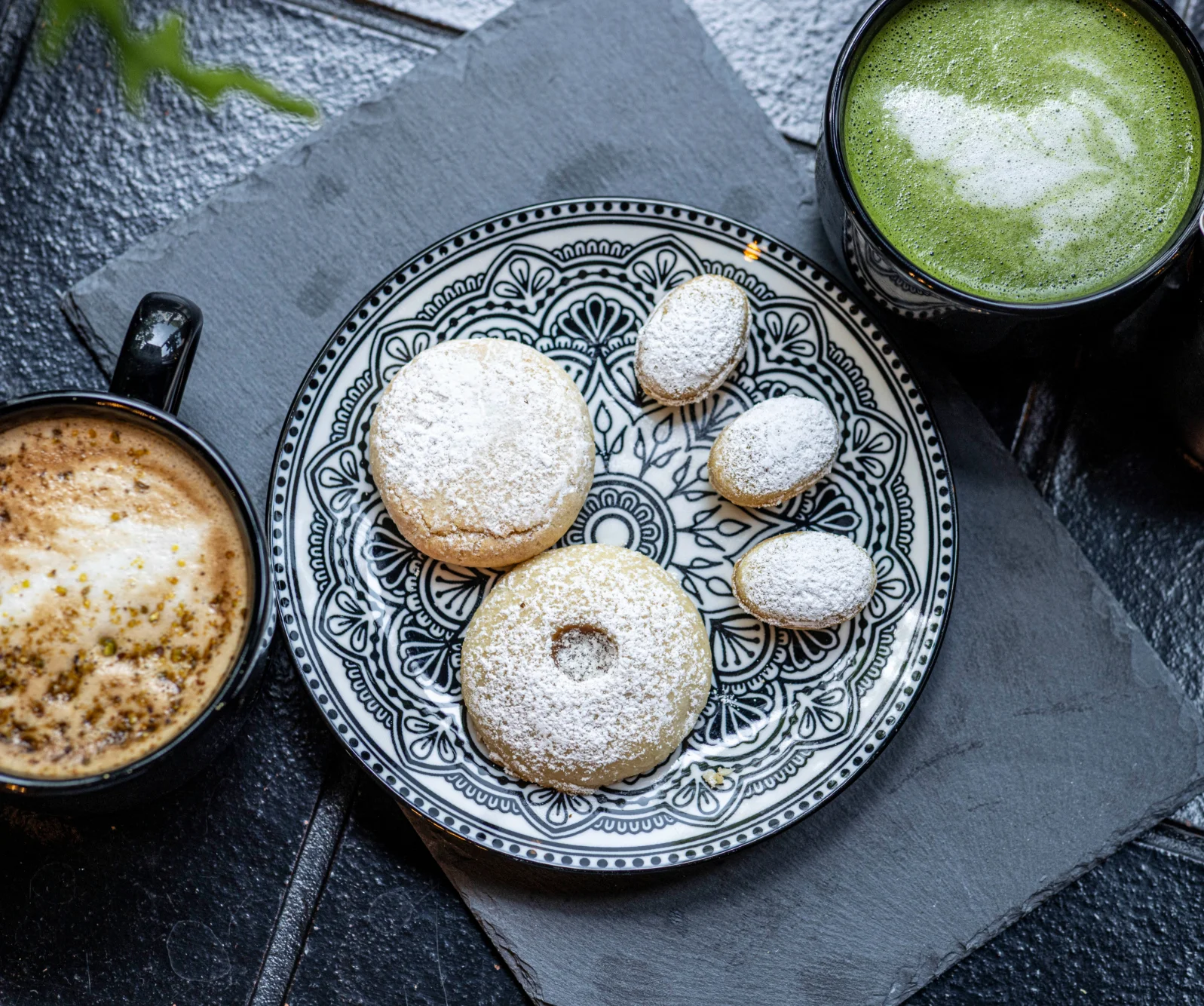 Plate of Middle Eastern maamoul cookies with coffee and matcha drinks