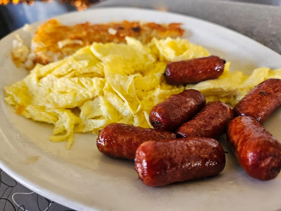 Scrambled eggs served with breakfast sausage links.