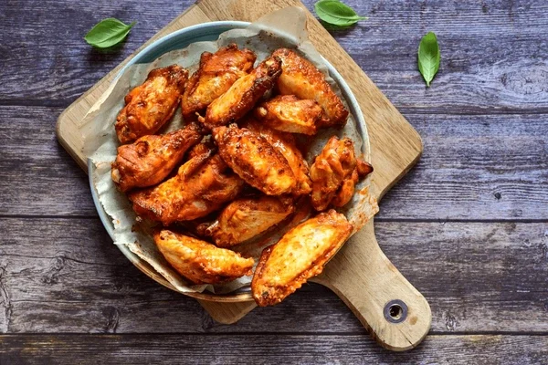 Crispy buffalo chicken wings served on a wooden platter