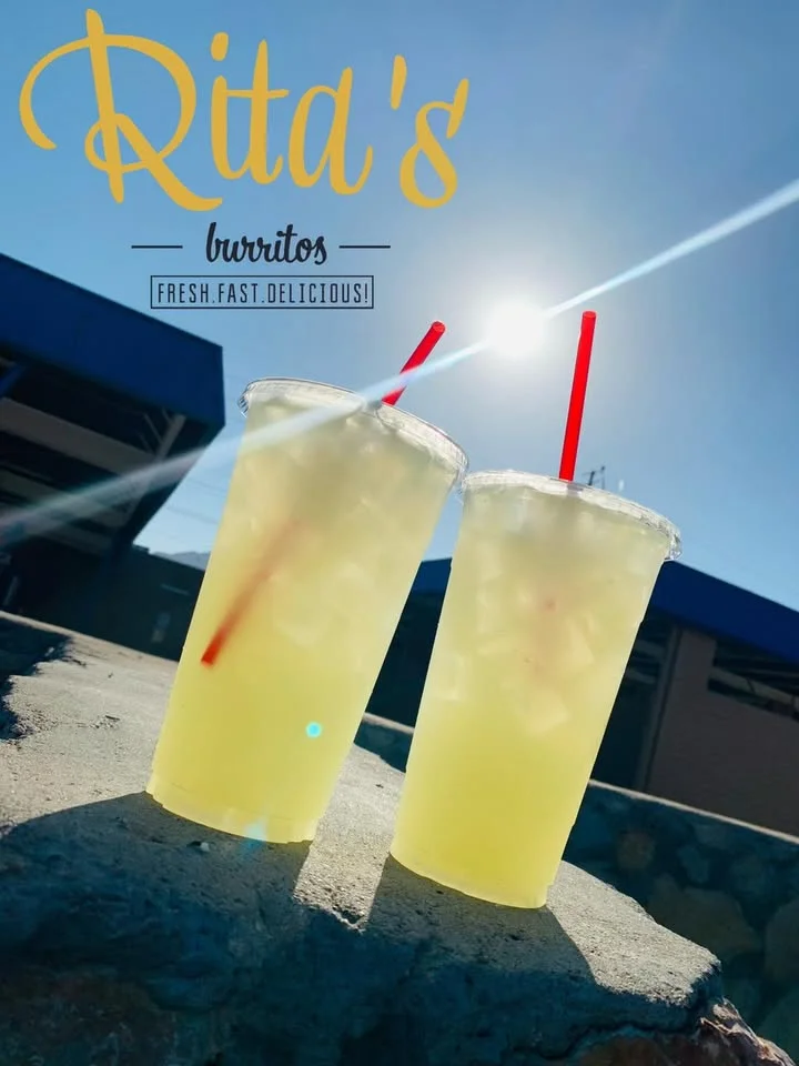 Two refreshing yellow drinks with ice, topped with red straws, set against a bright sunlit background.
