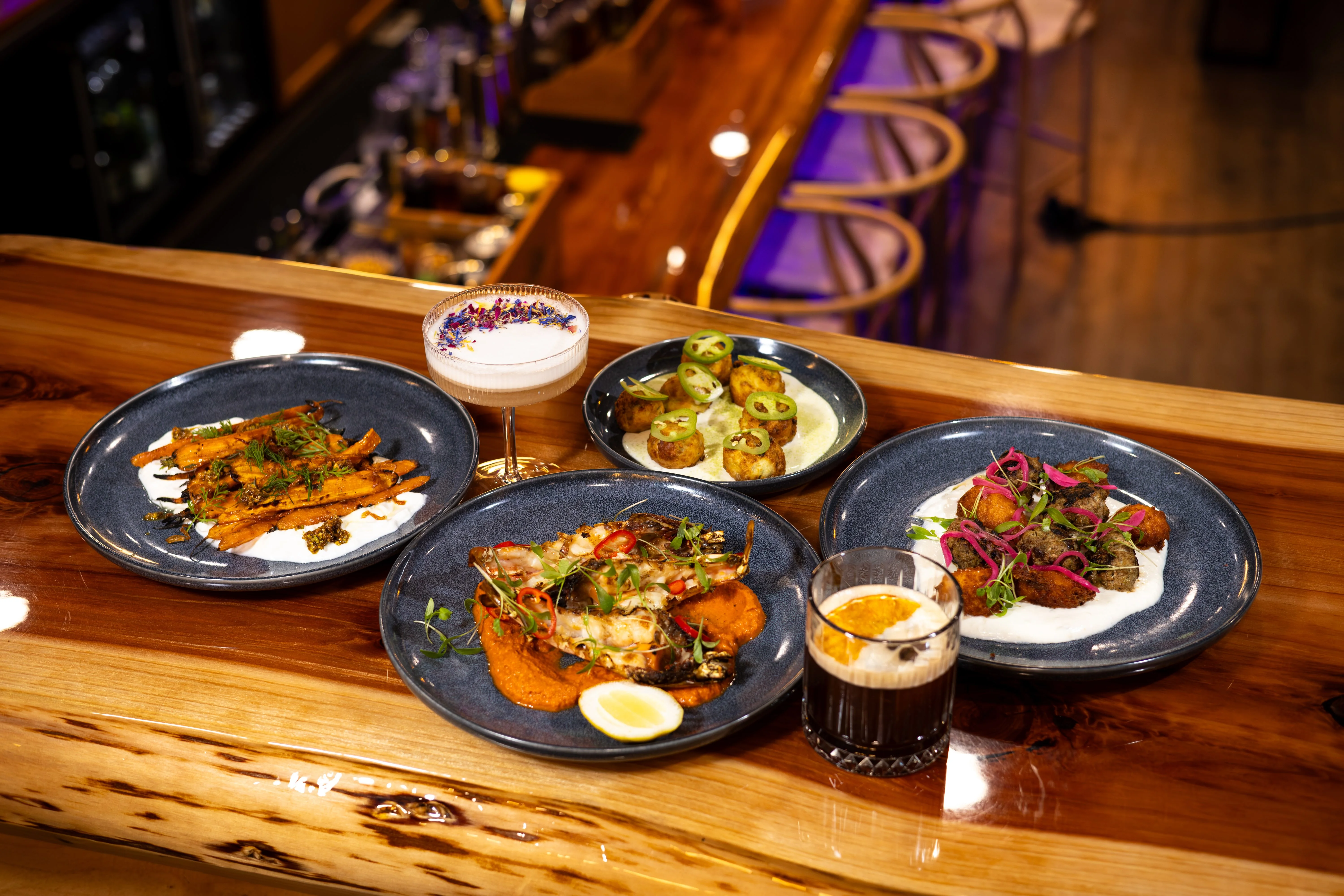 Assorted Indian dishes with cocktails on a wooden bar