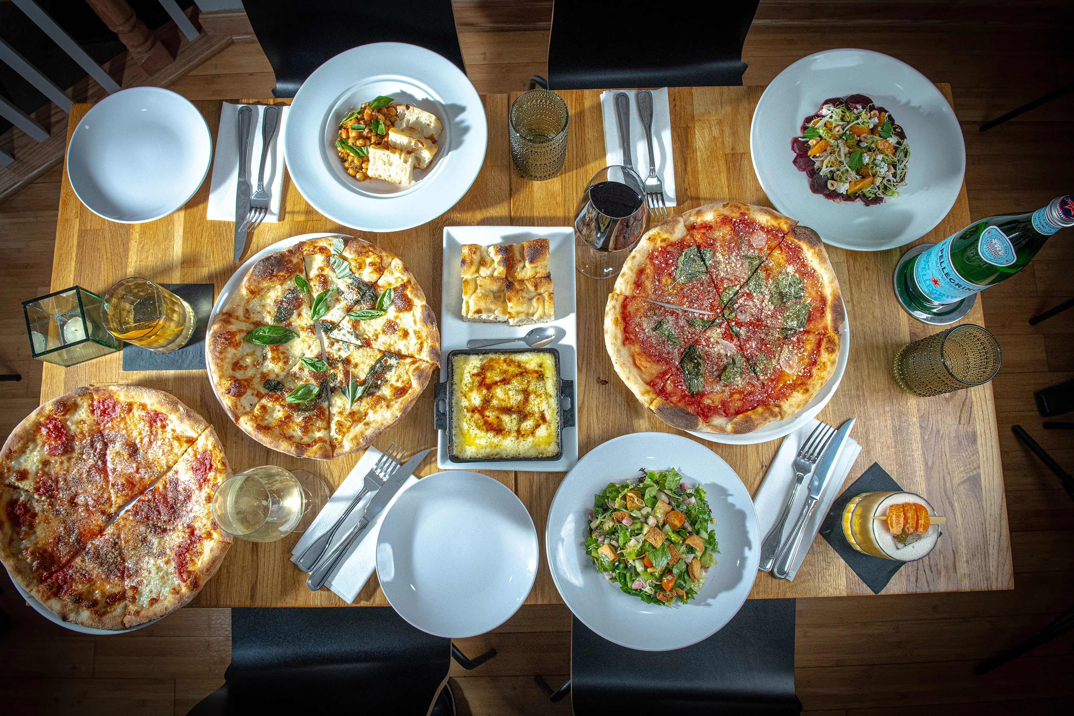 Assorted pizzas and salads on a wooden dining table