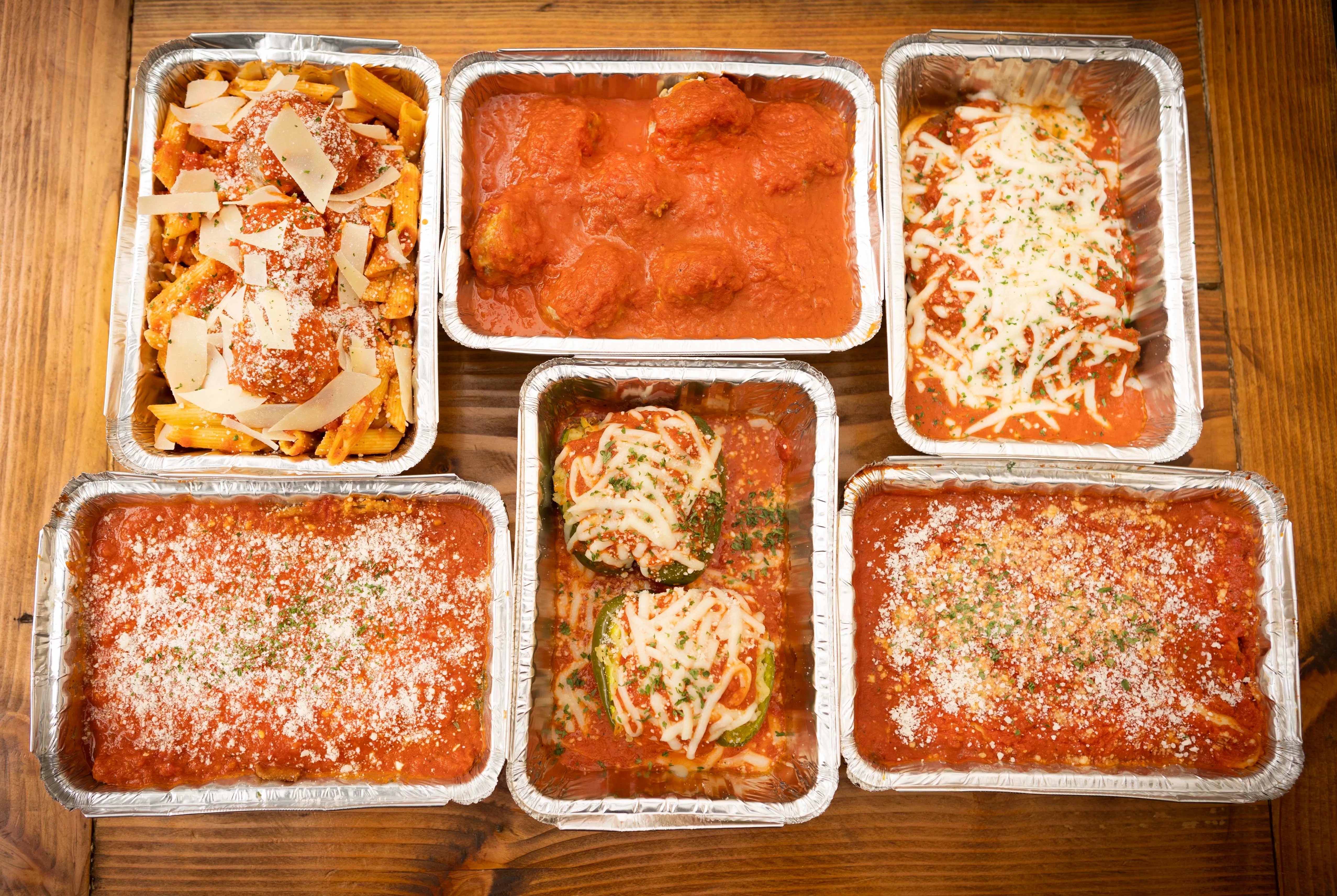 Italian comfort food featuring pasta, meatballs, and marinara sauce in foil trays