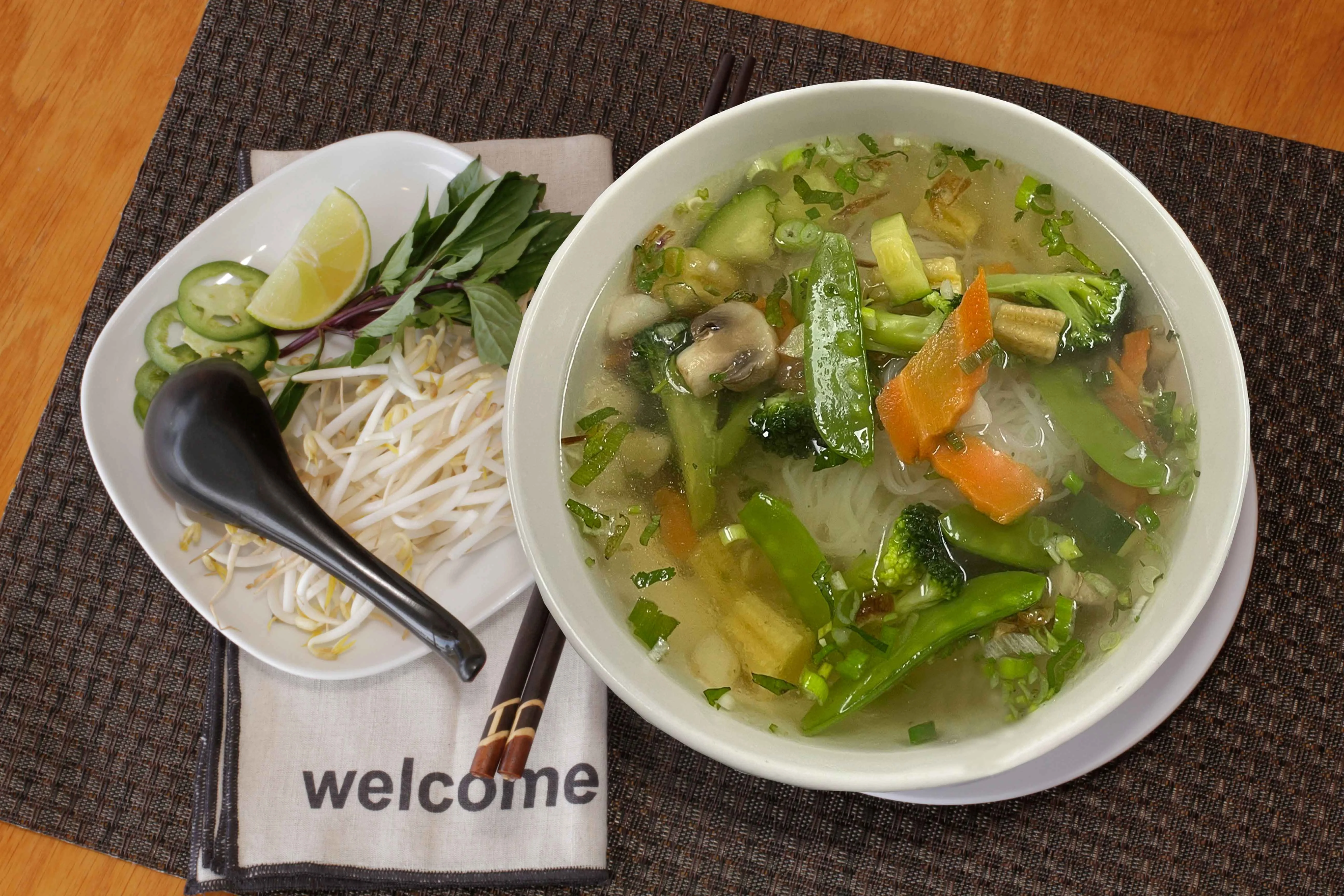 Bowl of Vietnamese vegetable pho with fresh herbs and lime