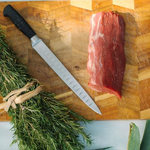 Chef's knife and fresh beef on a wooden cutting board