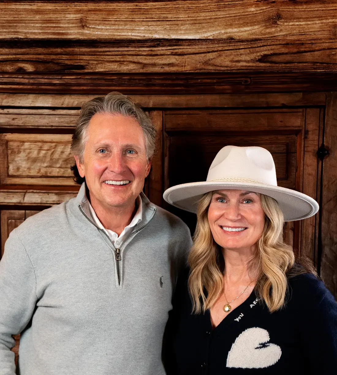 Two smiling individuals posing in a cozy wooden interior