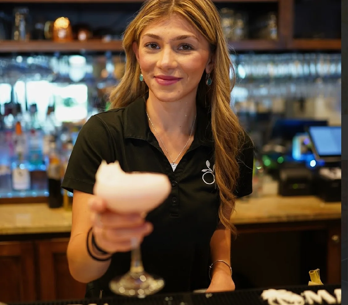 Bartender serving a pink cocktail at a stylish bar