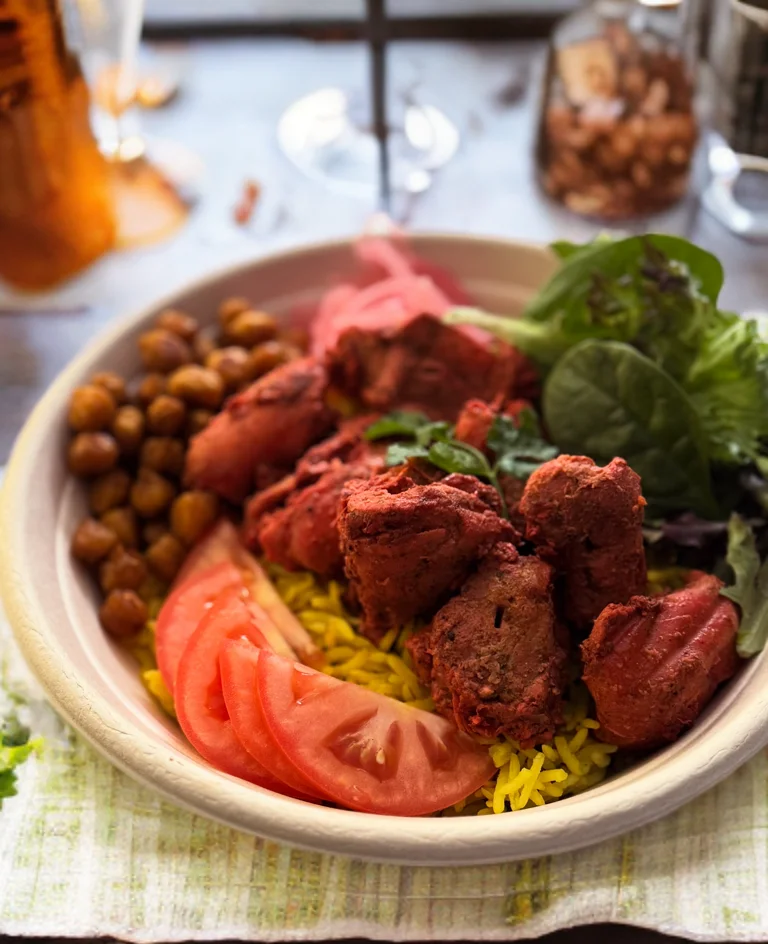 Plate of Indian biryani with tandoori chicken and fresh vegetables