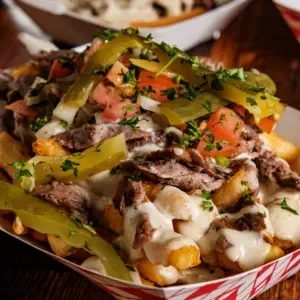 A delicious serving of loaded fries topped with meat, vegetables, and a creamy sauce.