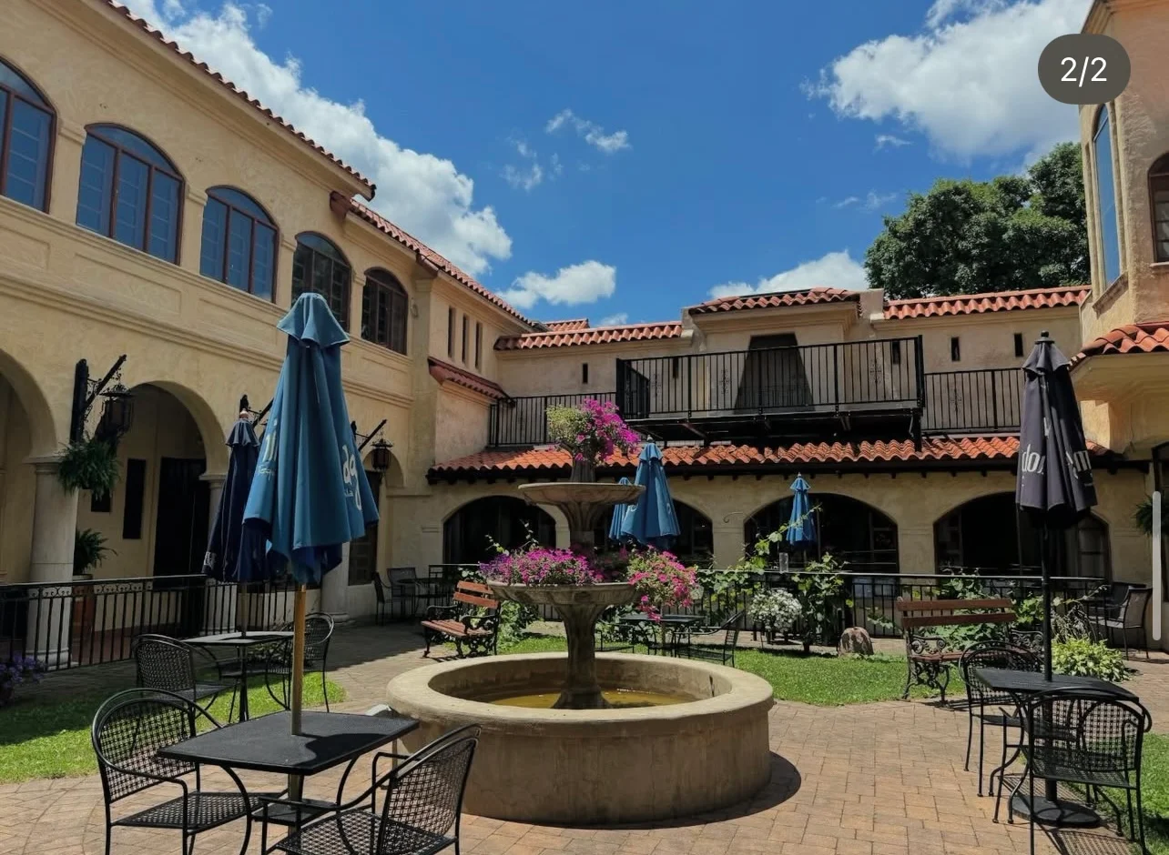 Outdoor courtyard dining area with tables and greenery.