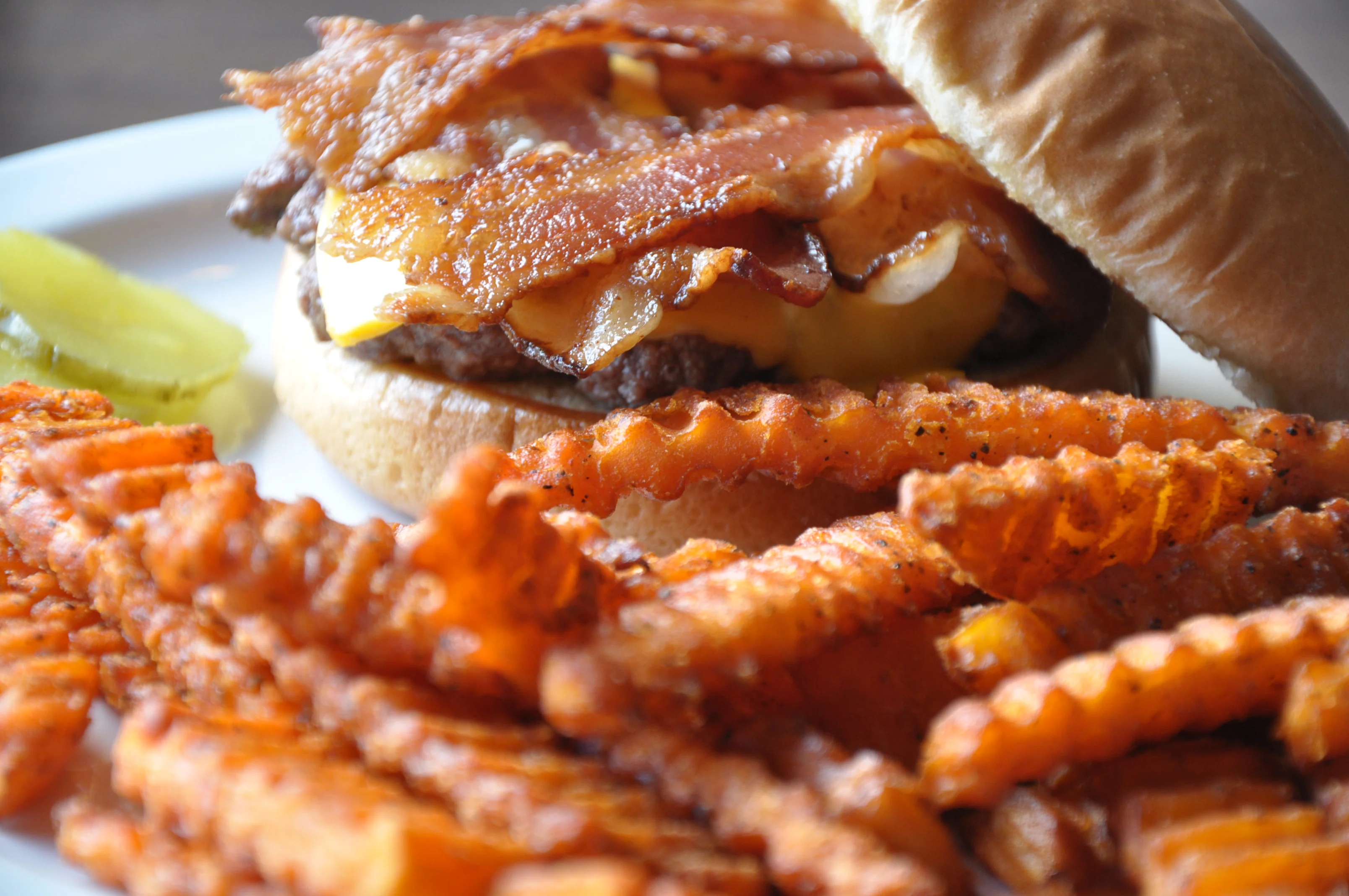Juicy cheeseburger with crispy bacon and sweet potato fries