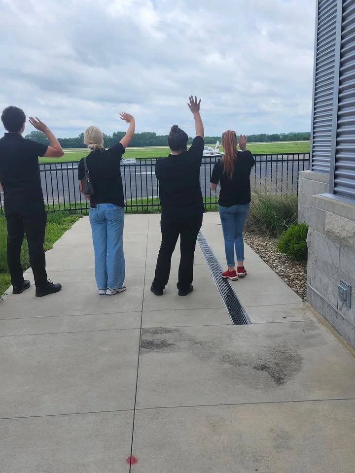 Group of people waving goodbye at an airport