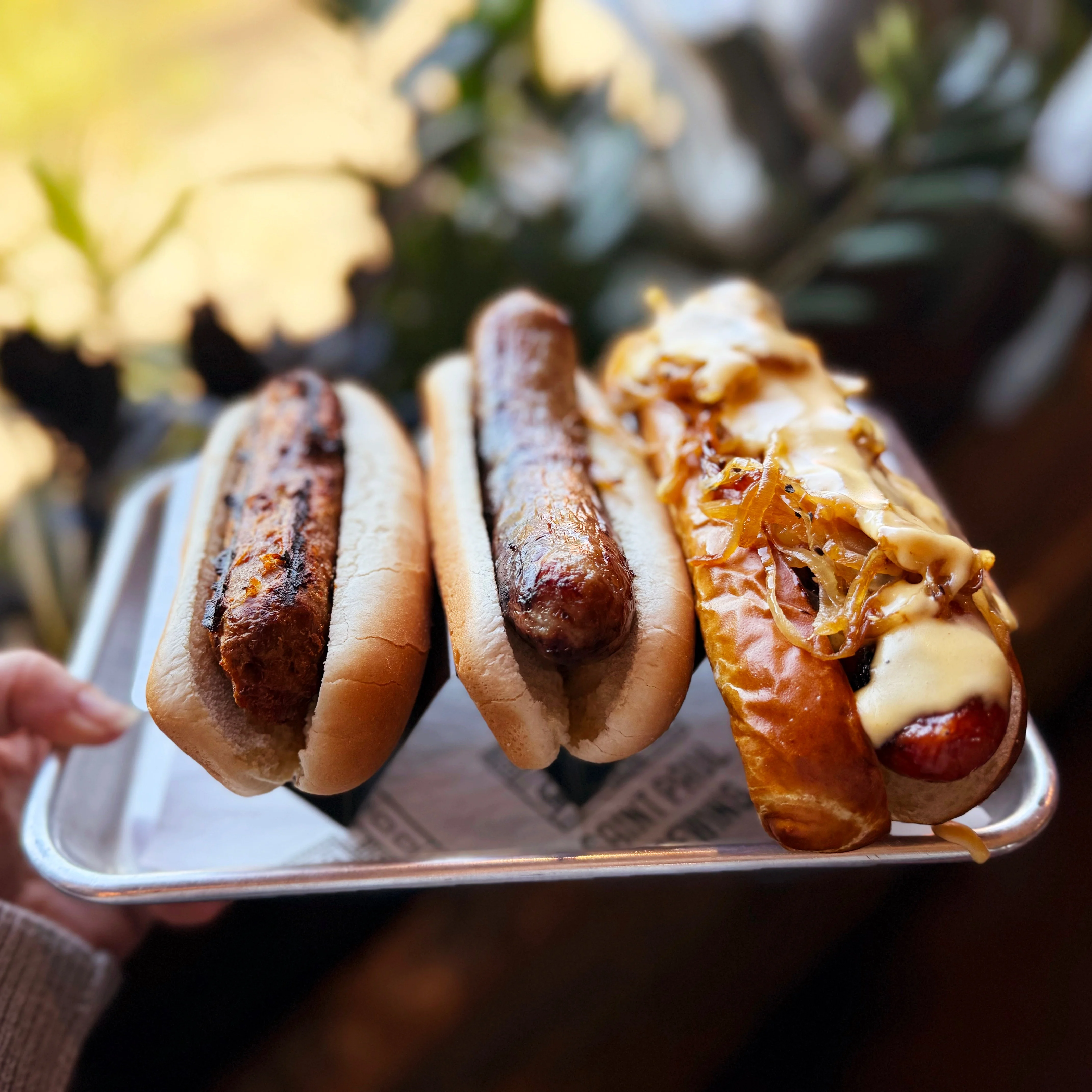Gourmet hot dogs with various toppings served on a tray