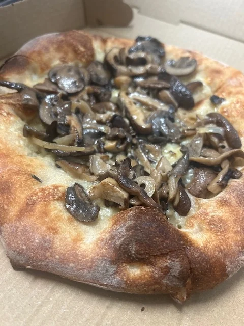 A pizza featuring a crust topped with sautéed mushrooms, giving it a rich and earthy flavor. The edges are crispy and well-baked.