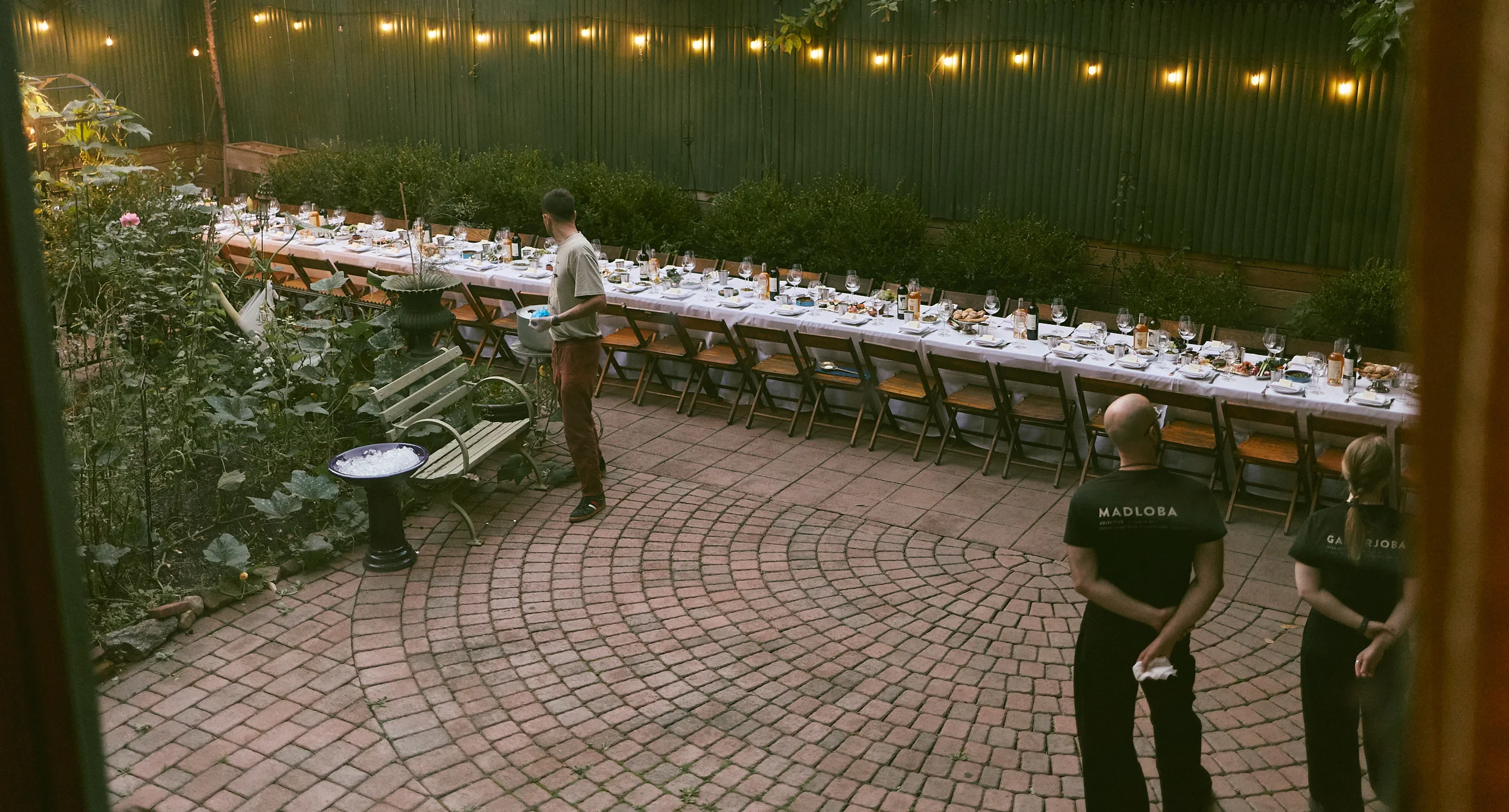 Garden restaurant patio with long communal dinner table and string lights