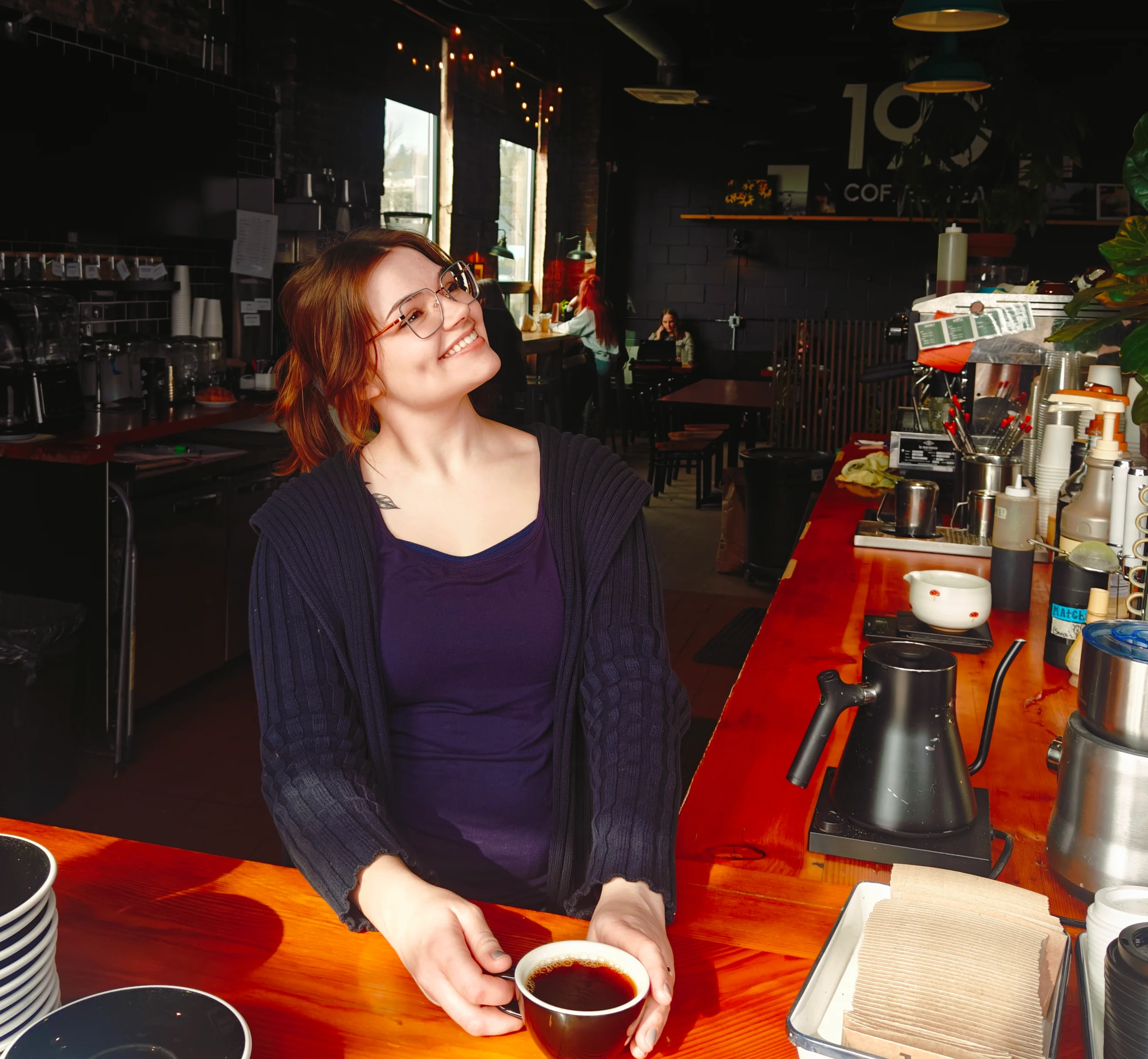 Barista smiling with coffee in a cozy café setting