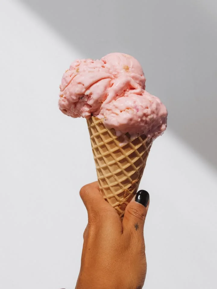 Delicious strawberry ice cream cone in hand