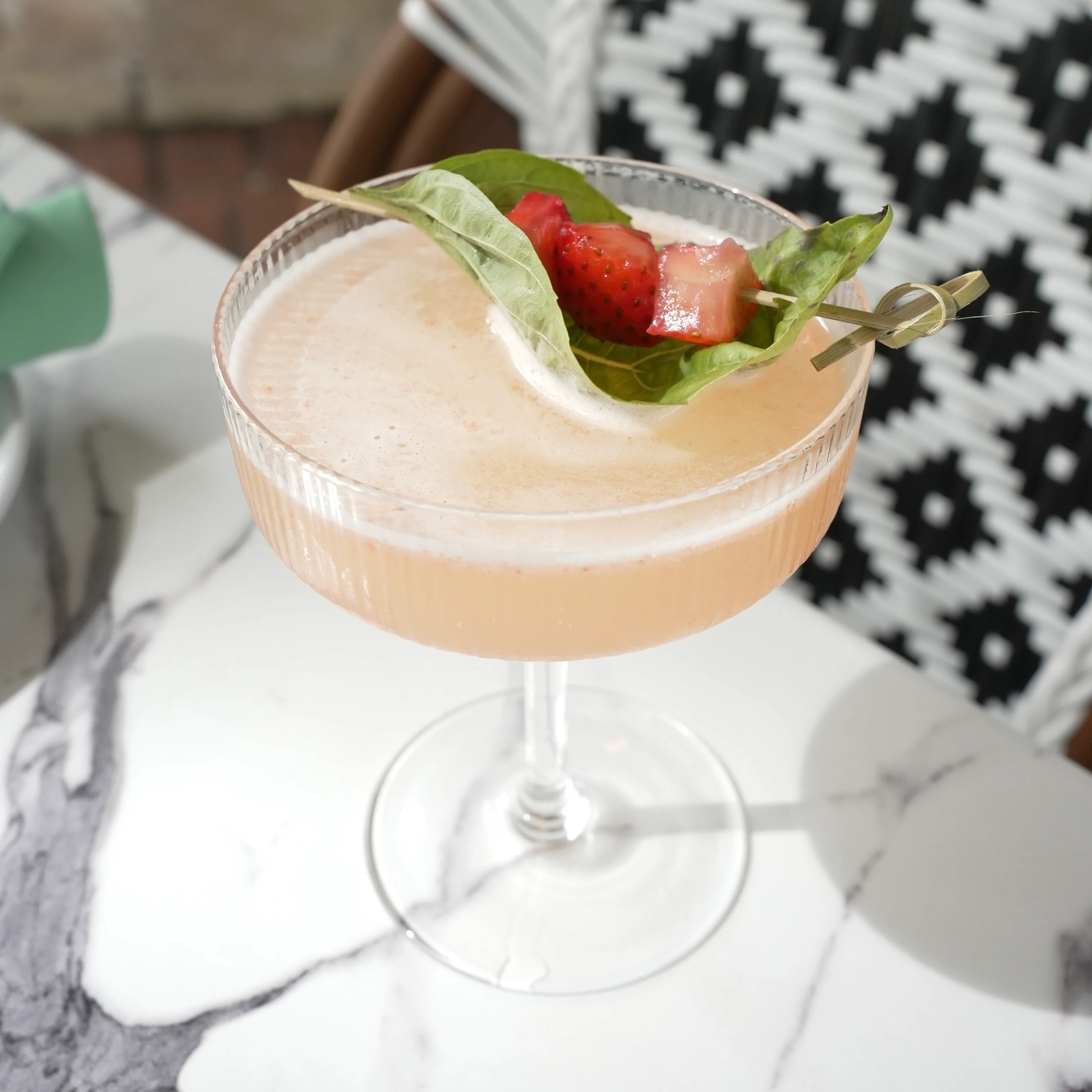 Craft cocktail with strawberries and basil in a stylish glass