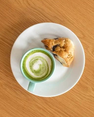 Matcha latte served with a scone on a white plate