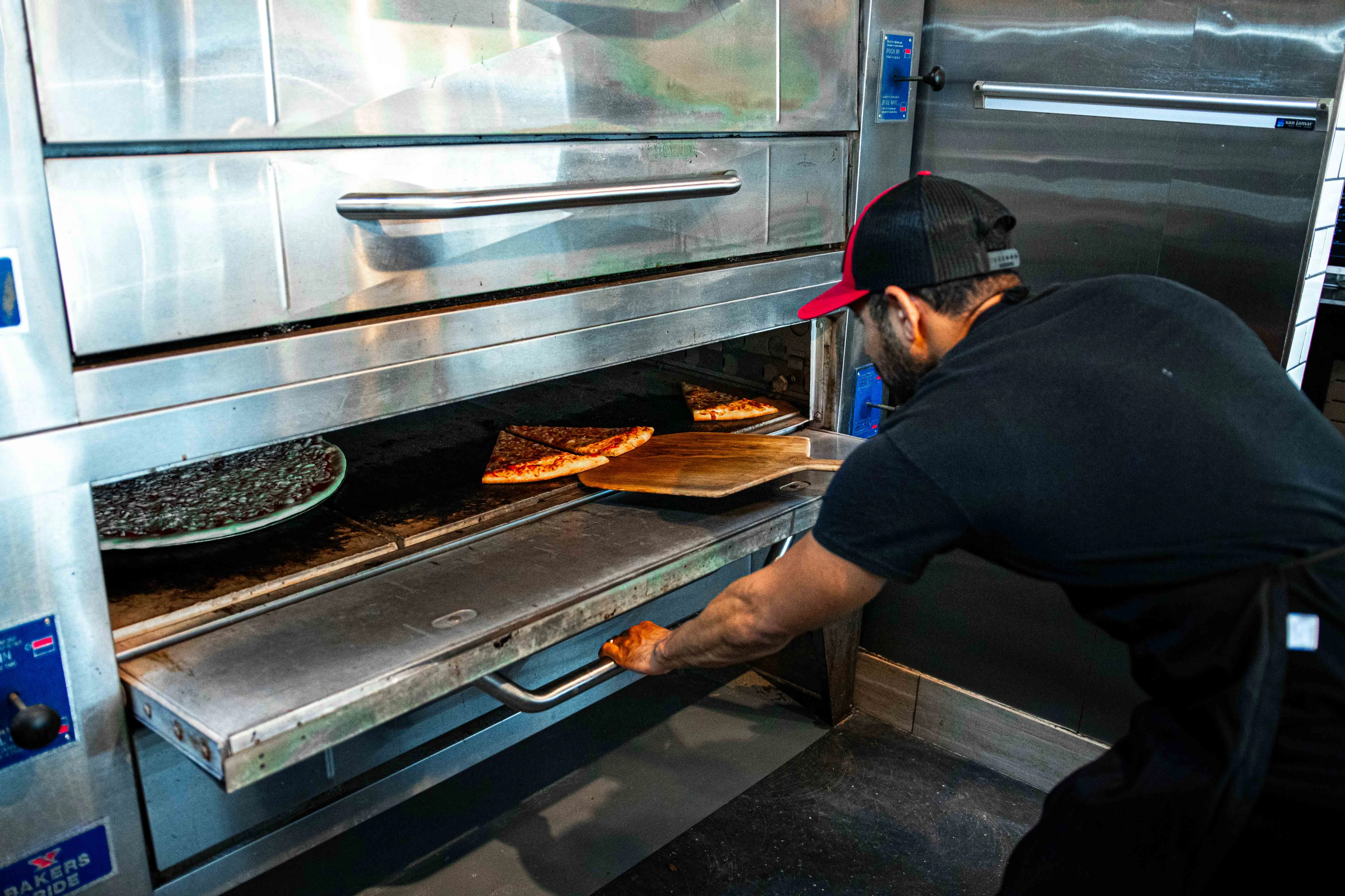 Pizza being pulled from a commercial oven
