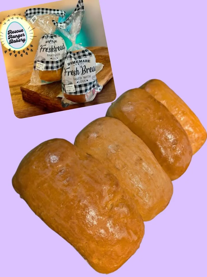 Three freshly baked loaves of bread, resting on a colorful background. The loaves have a shiny, golden-brown crust.