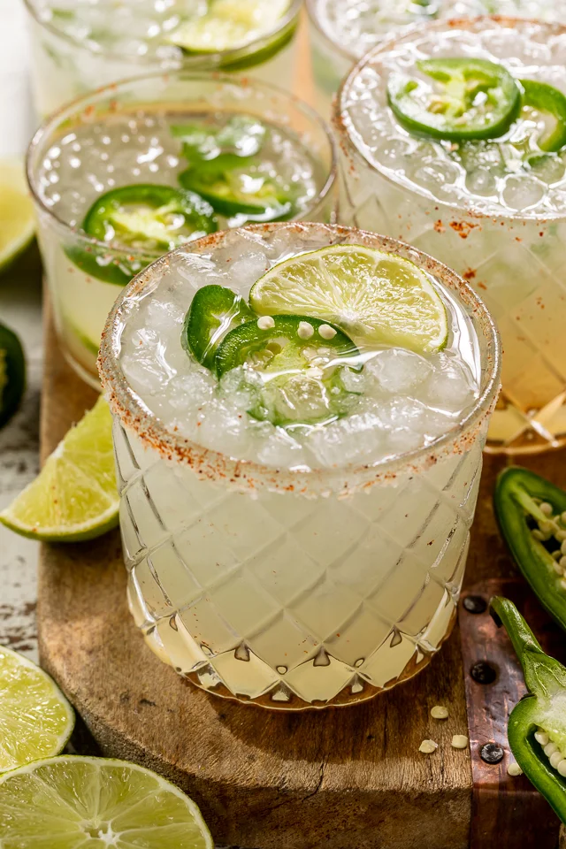 A vibrant pitcher of spicy jalapeño margaritas with garnishes.
