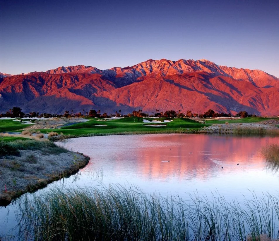 Scenic view of mountains reflecting in a tranquil golf course lake