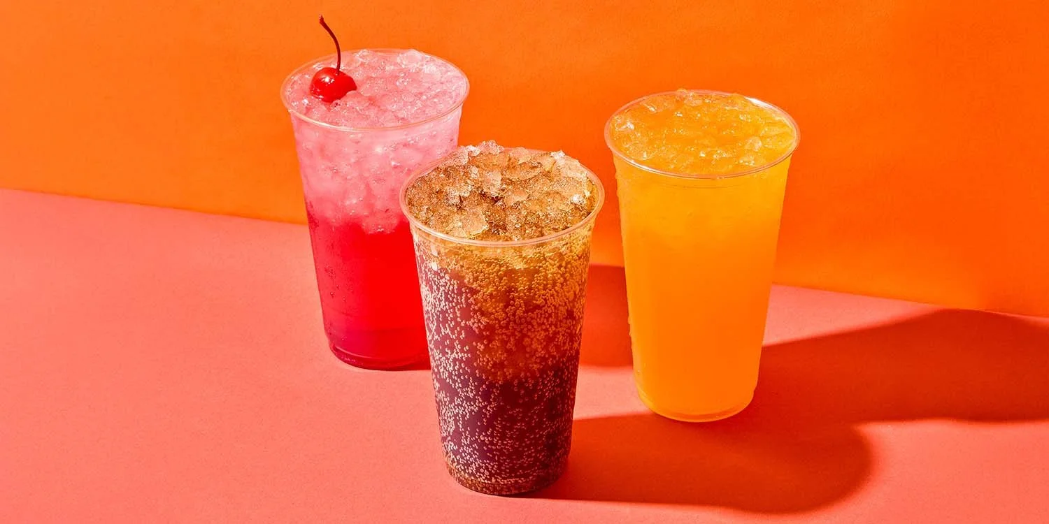 Colorful assortment of refreshing soft drinks in clear cups