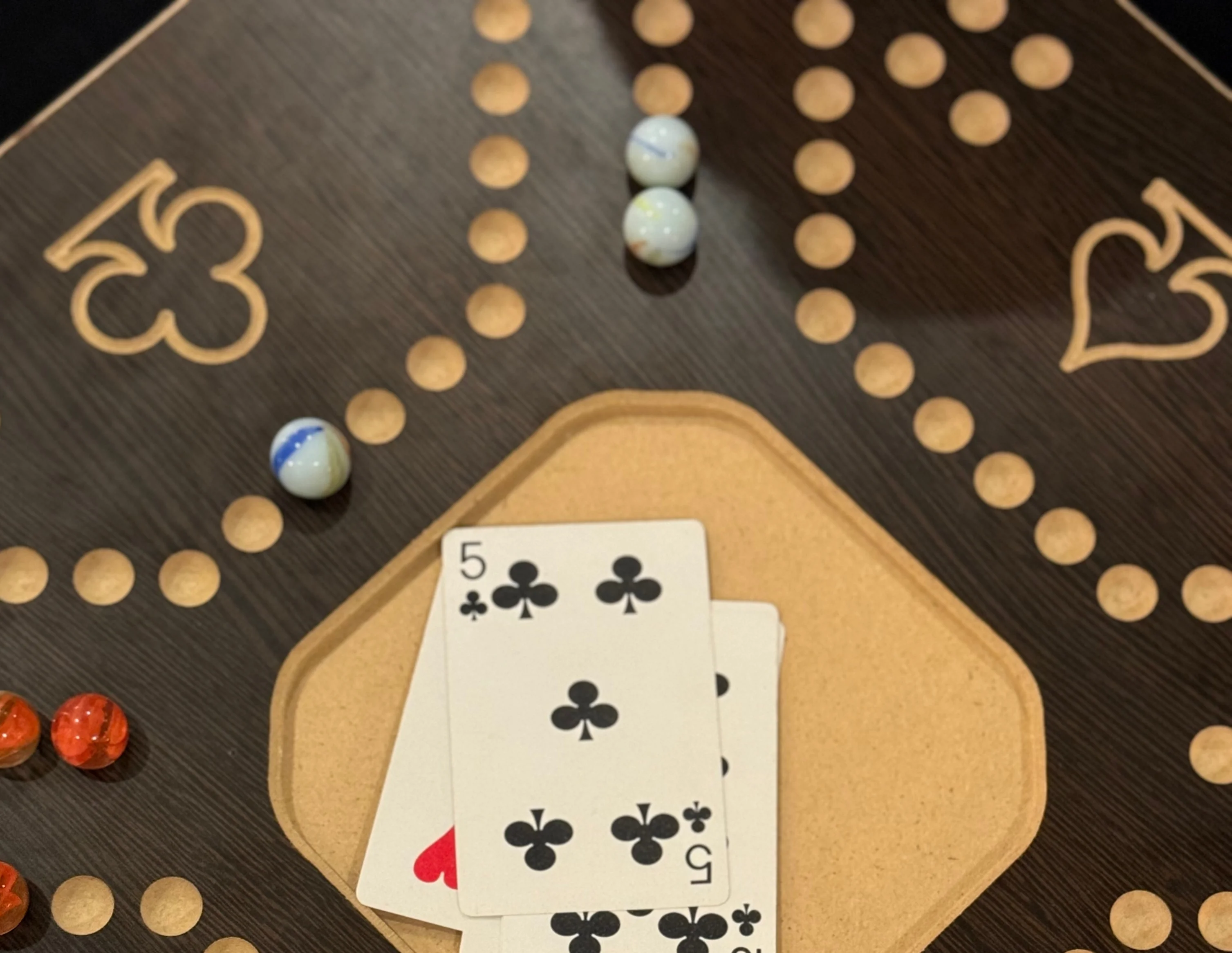 Playing cards on a wooden board game with colorful marbles
