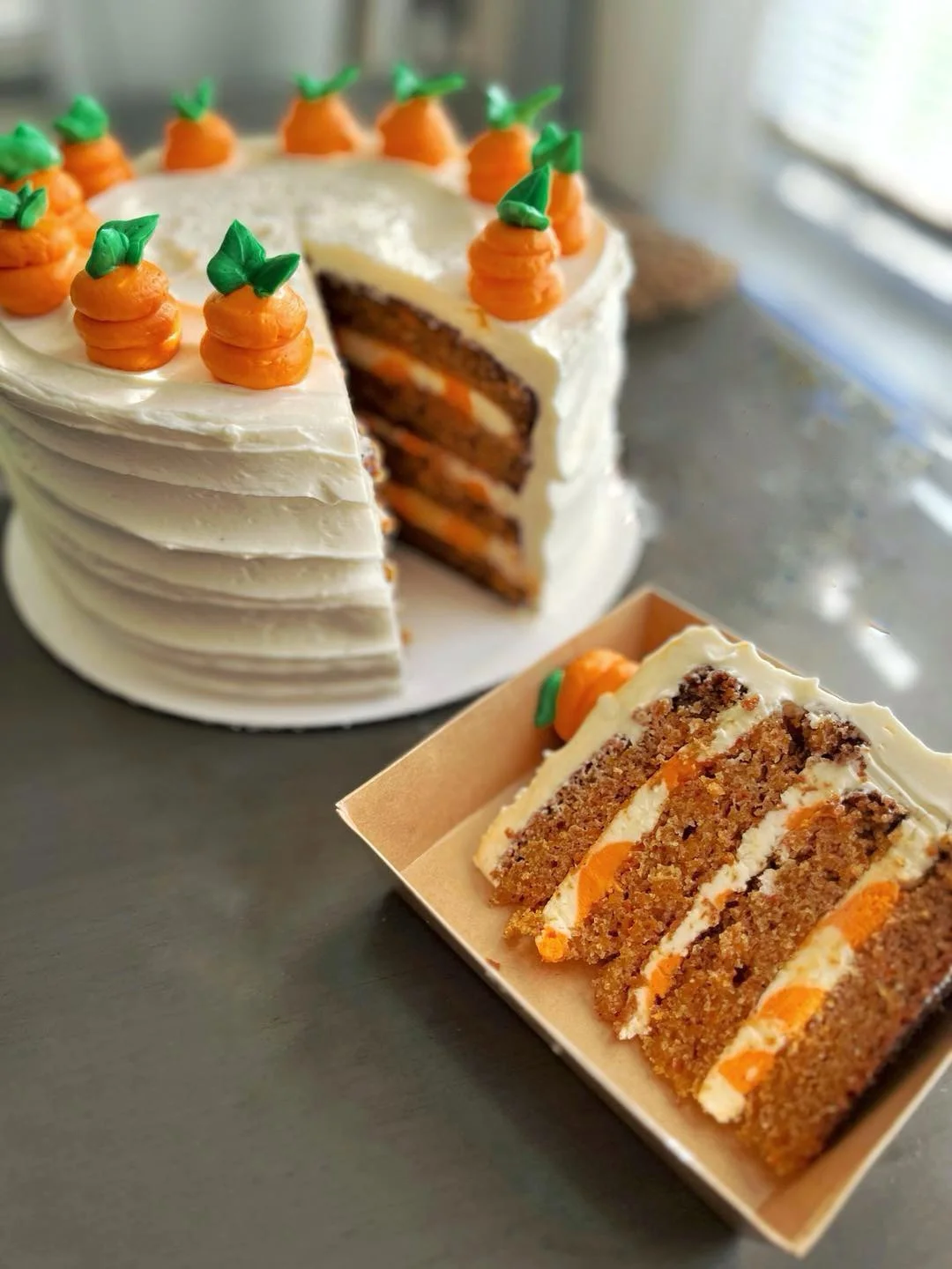 Layered carrot cake with cream cheese frosting and decorative carrots