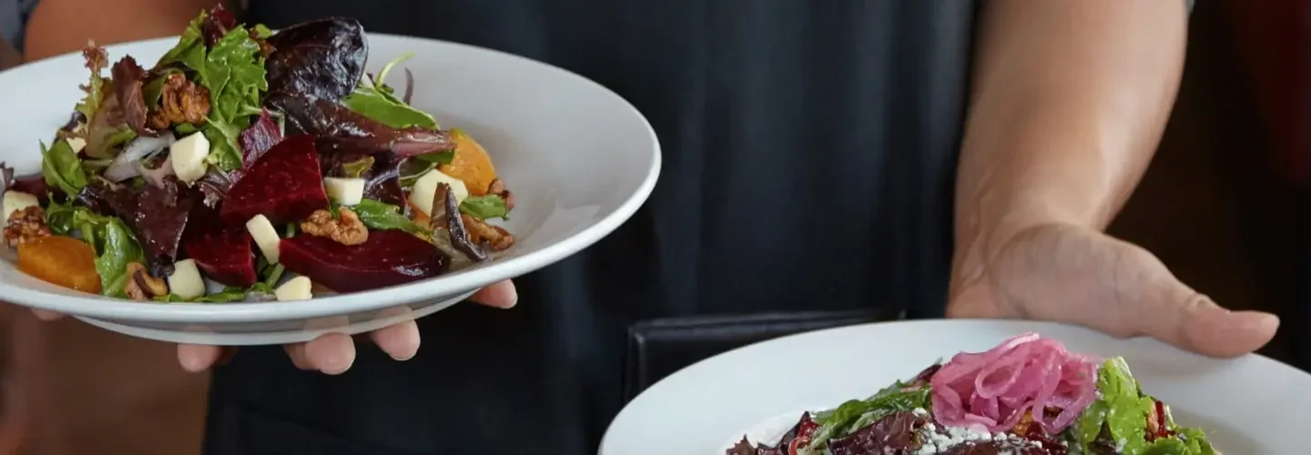 Server holding a Beet Salad and Mixta Salad