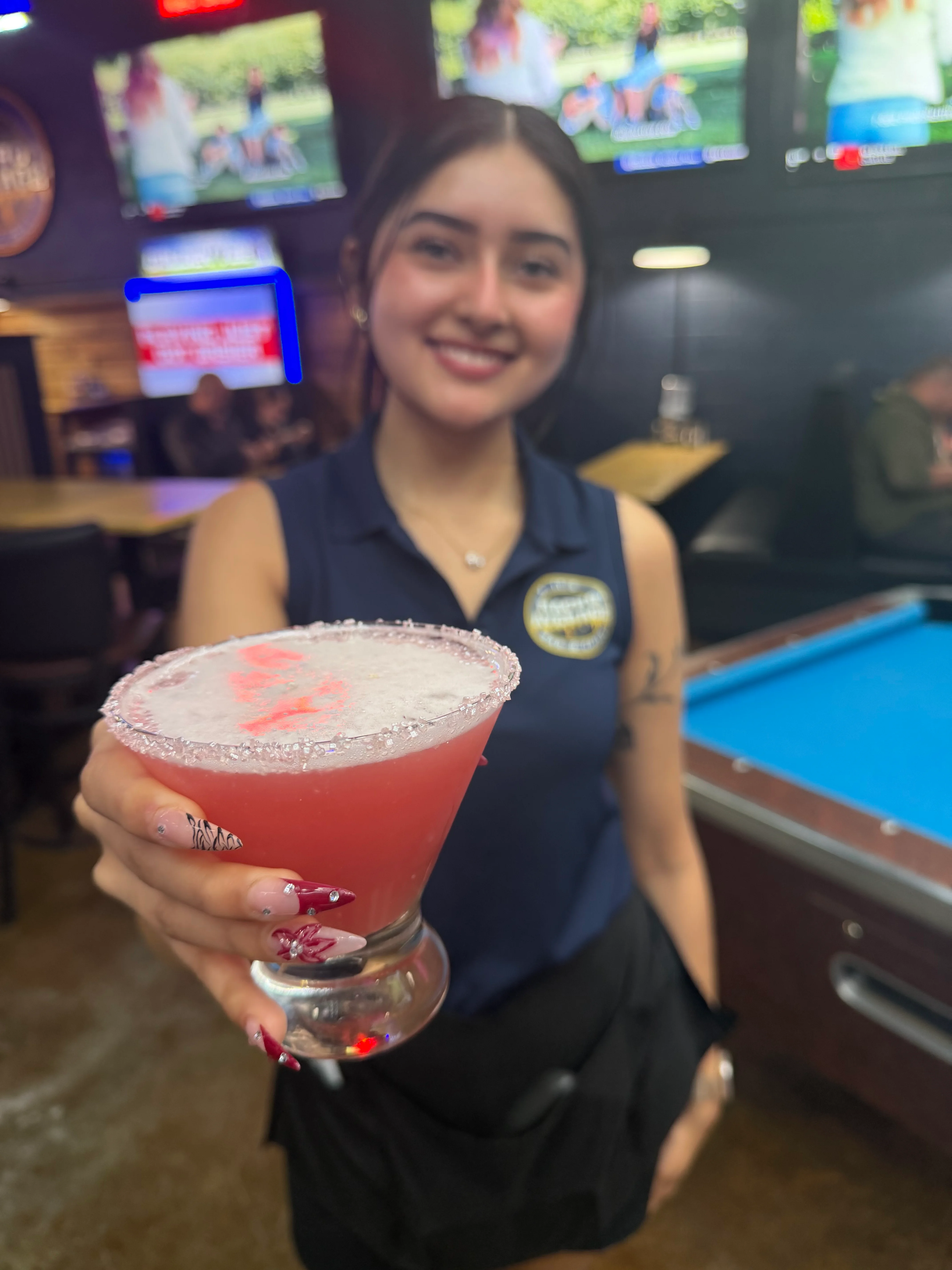 Bartender serving a vibrant cocktail at a lively bar
