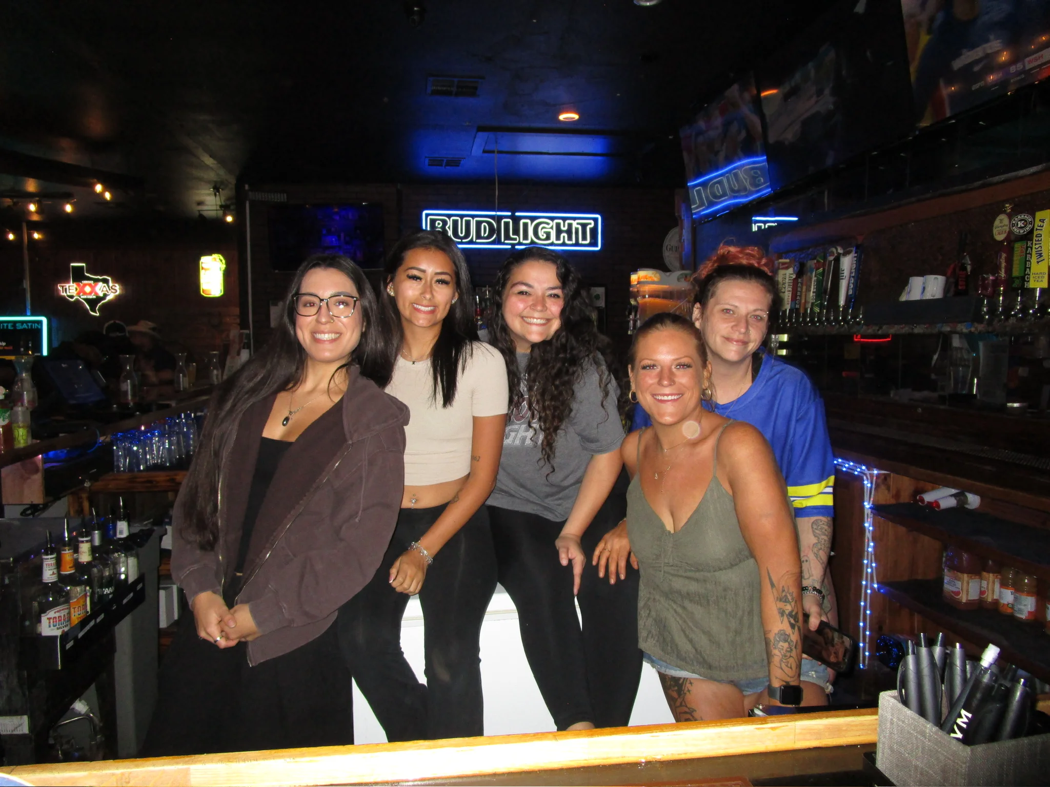 Group of friends posing in a lively bar with pool table