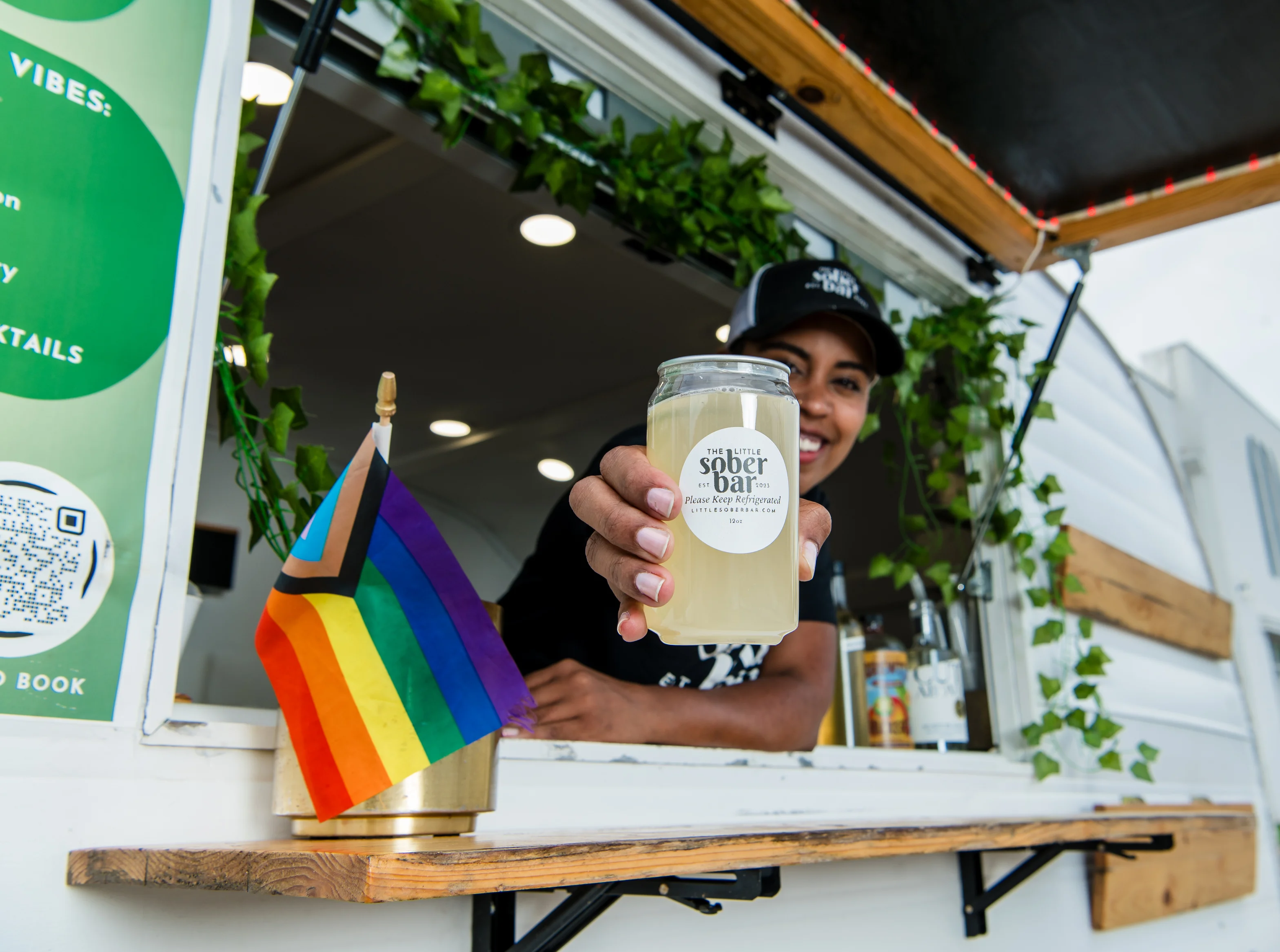 Person holding a drink in a branded koozie from The Little Sober Bar