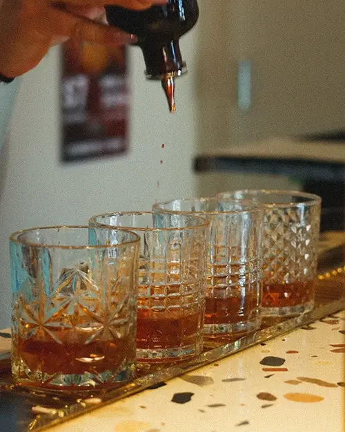 Four glasses with old fashioneds being made in them