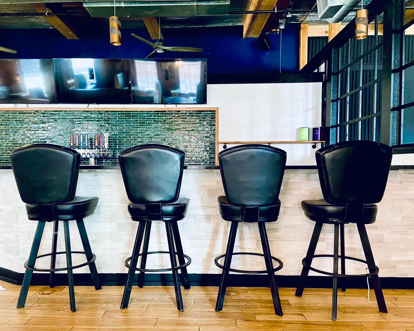 Modern bar counter with black stools and green tile backsplash