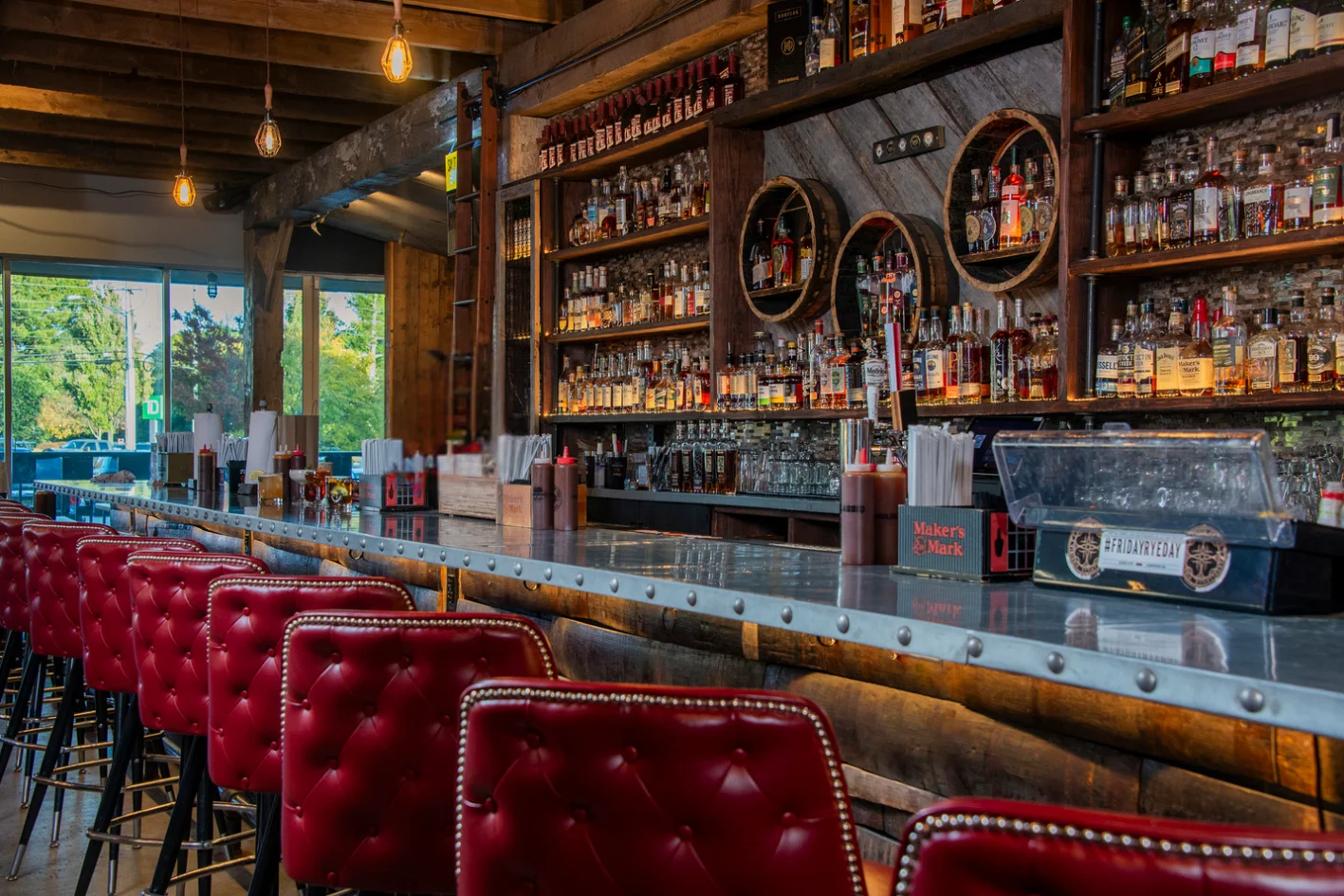 Stylish bar interior with whiskey bottles and red leather stools