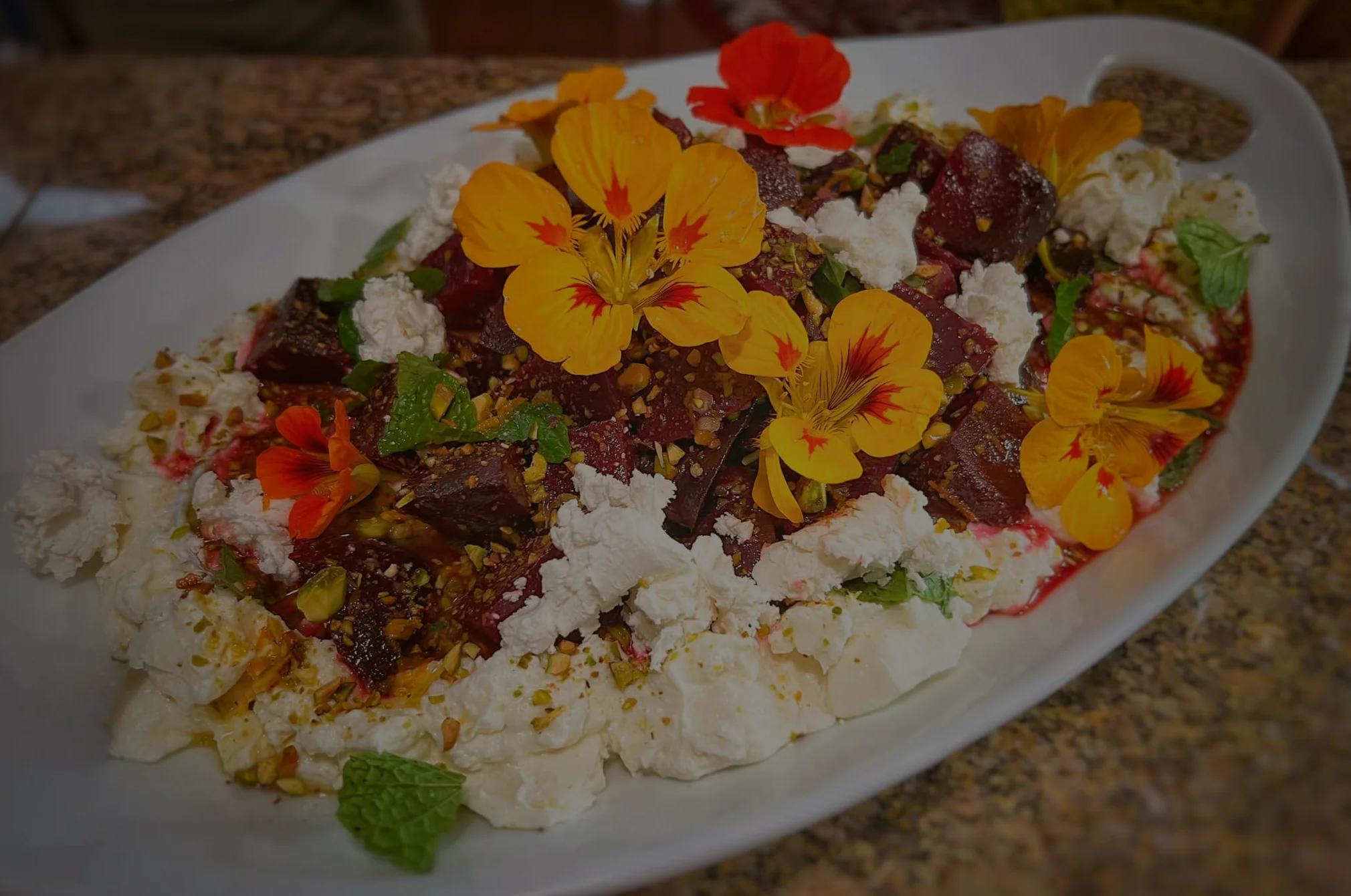 Colorful beet salad with goat cheese and edible flowers