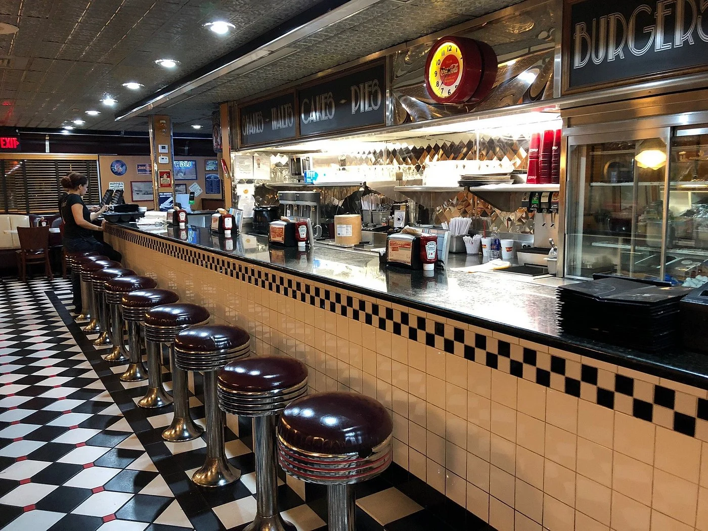 Classic Moonlite Diner counter with chrome stools, checkerboard floor, open kitchen