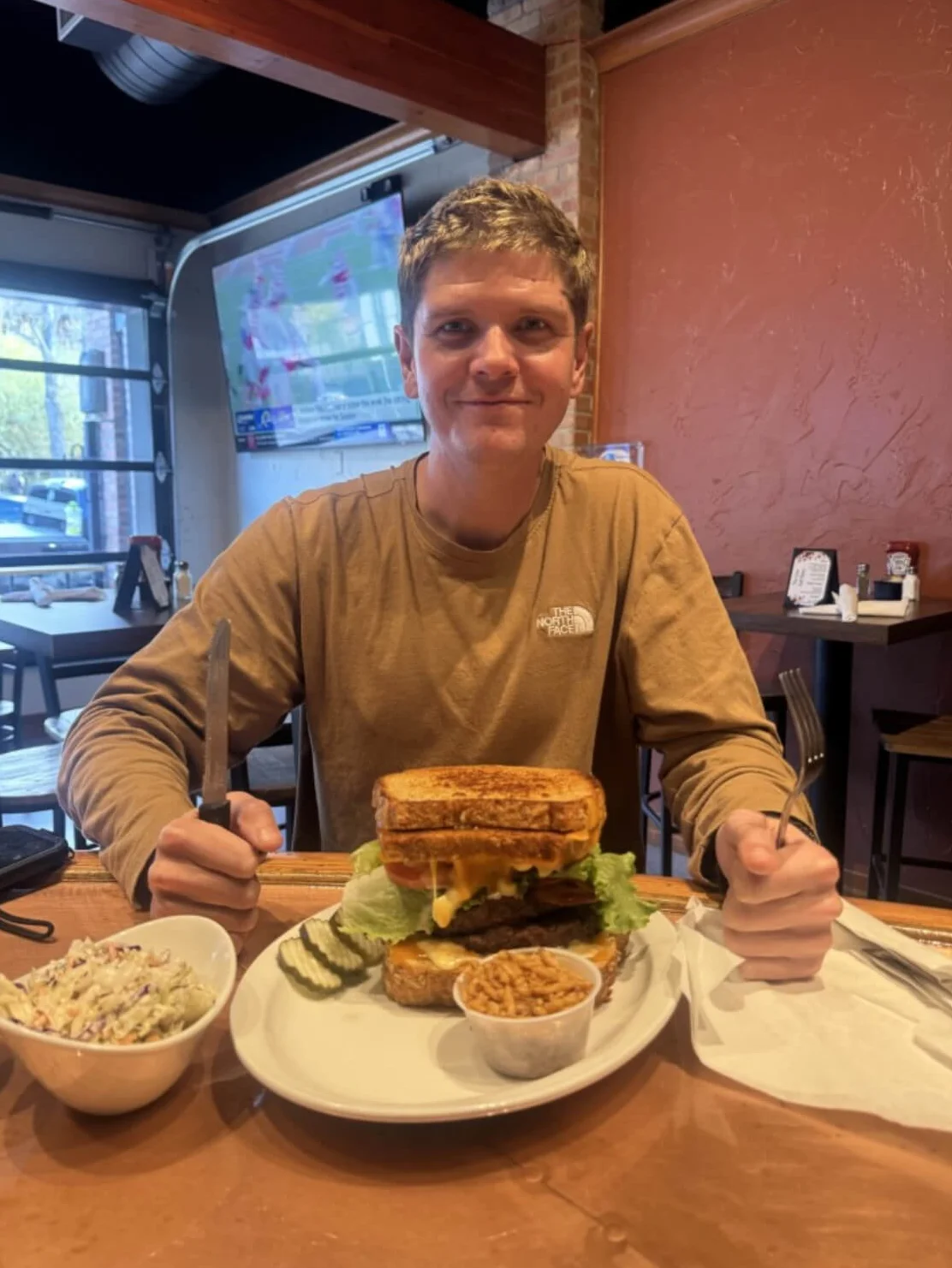 Giant cheeseburger with lettuce and pickles in a cozy restaurant setting