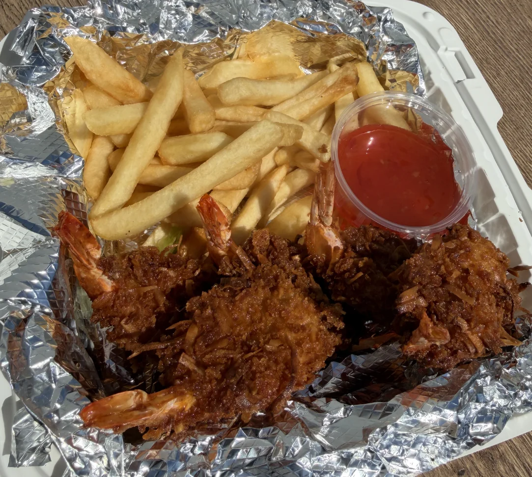 Fried shrimp with fries and dipping sauce in a takeout container