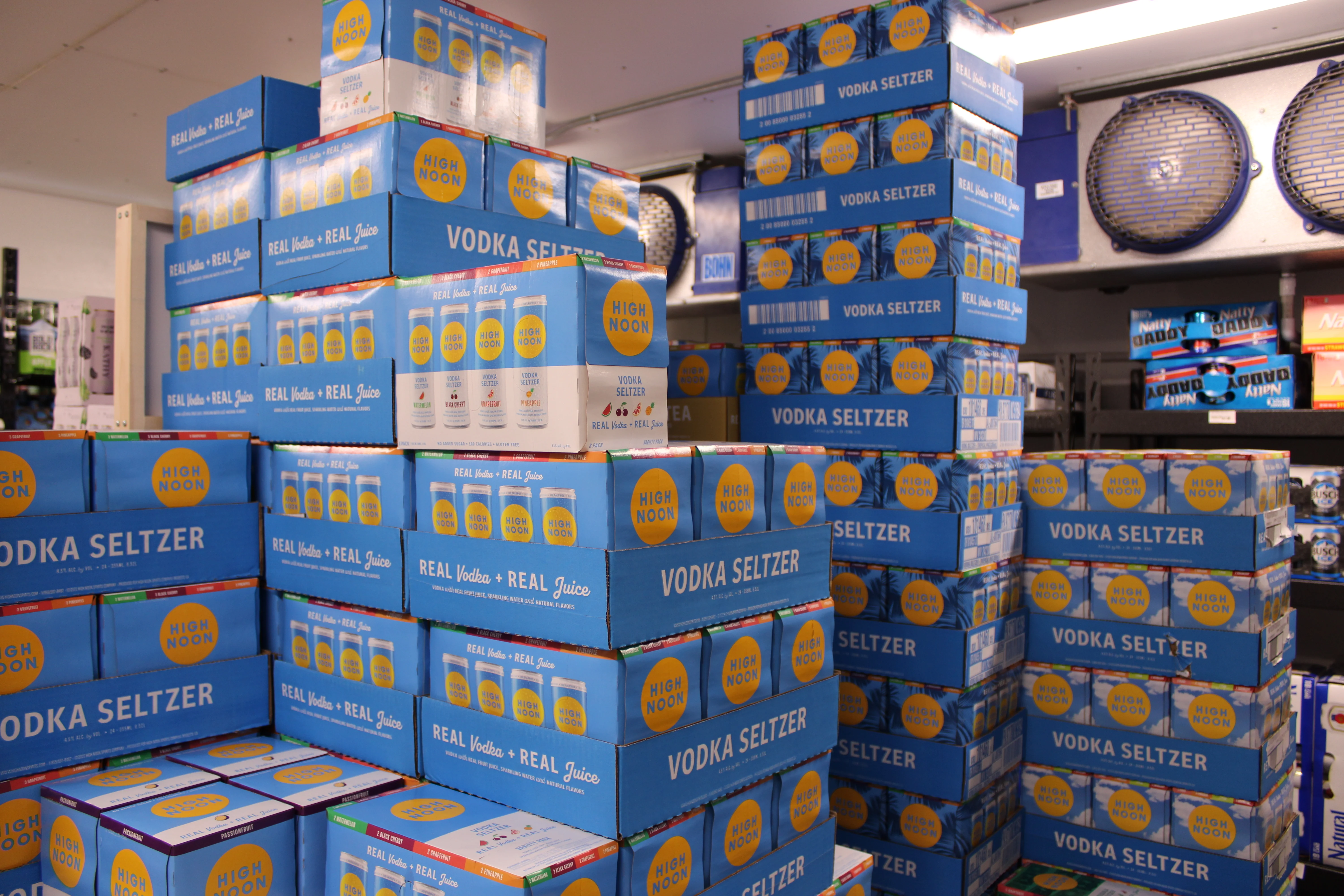 Stacked boxes of High Noon vodka seltzer in a retail space