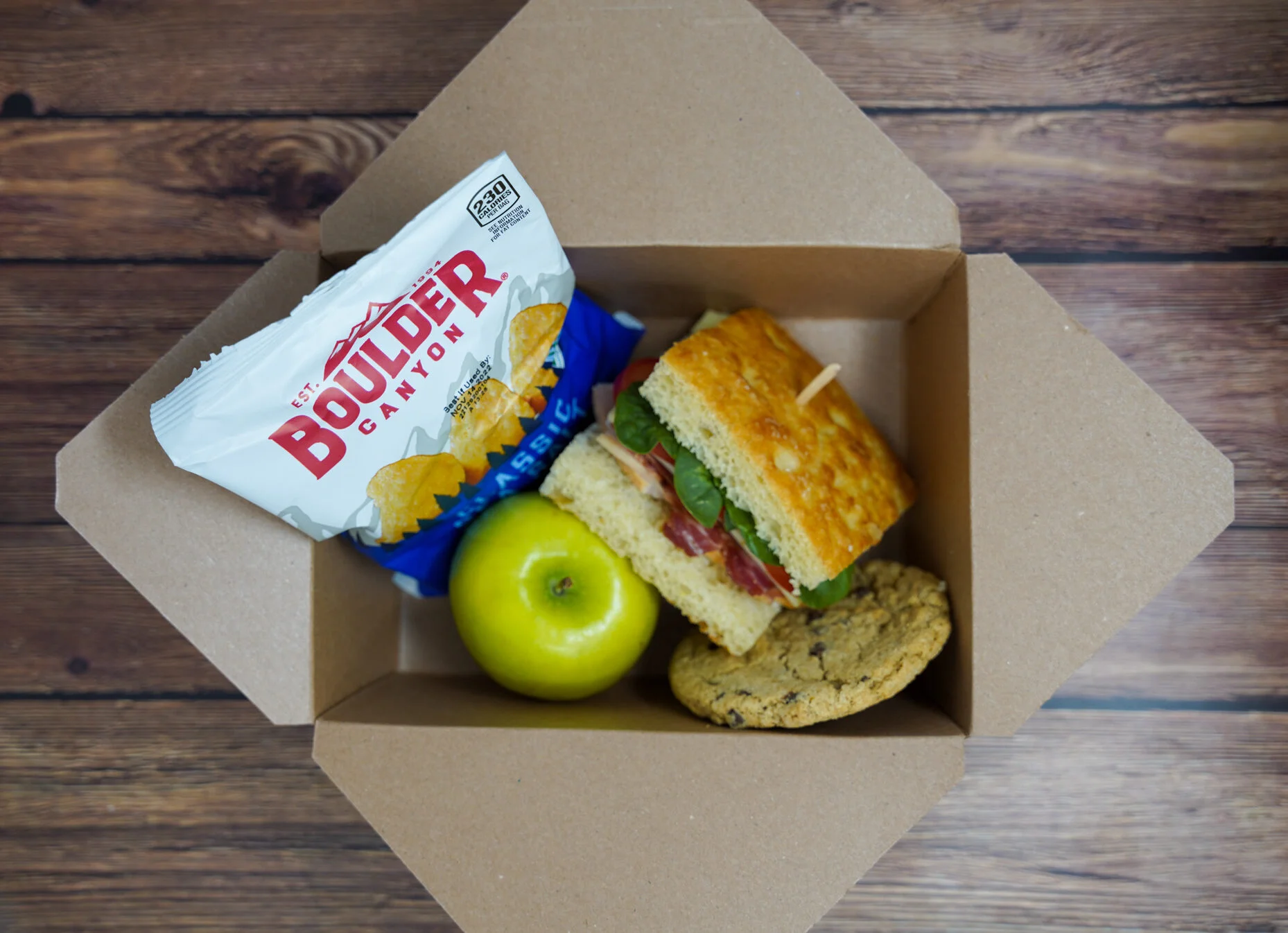 Gourmet sandwich box with chips, apple, and cookie