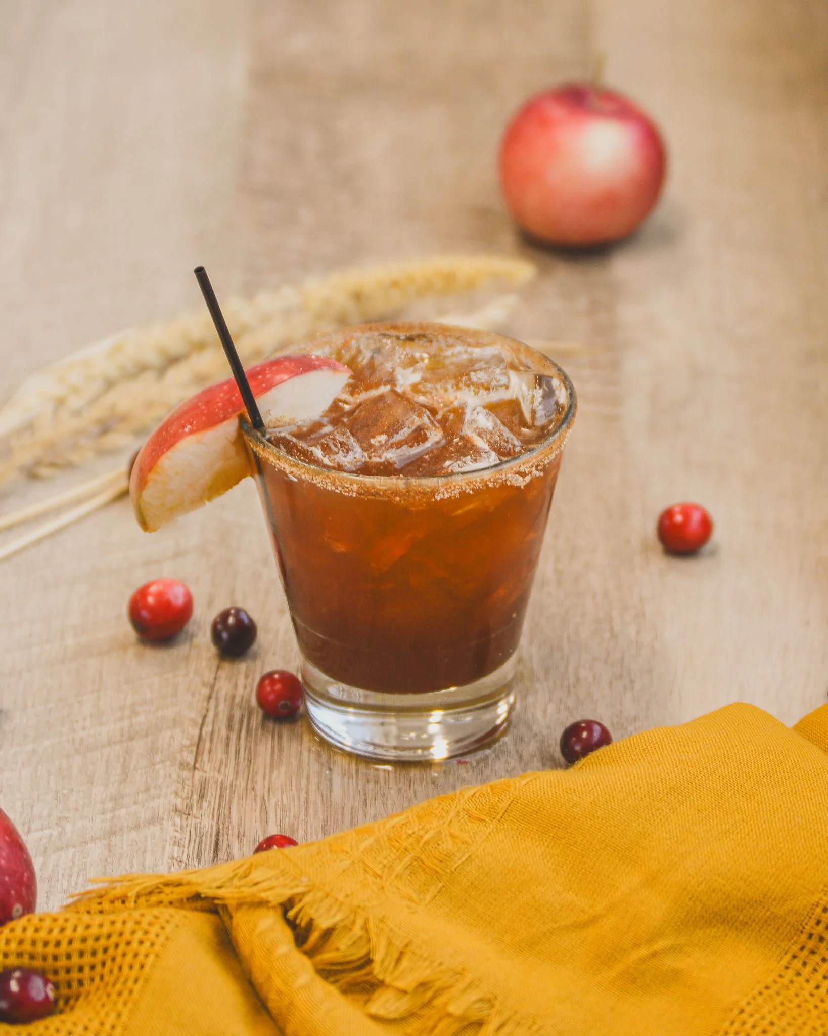 Harvest Spice cocktail with fall items like cranberries and apples in the background
