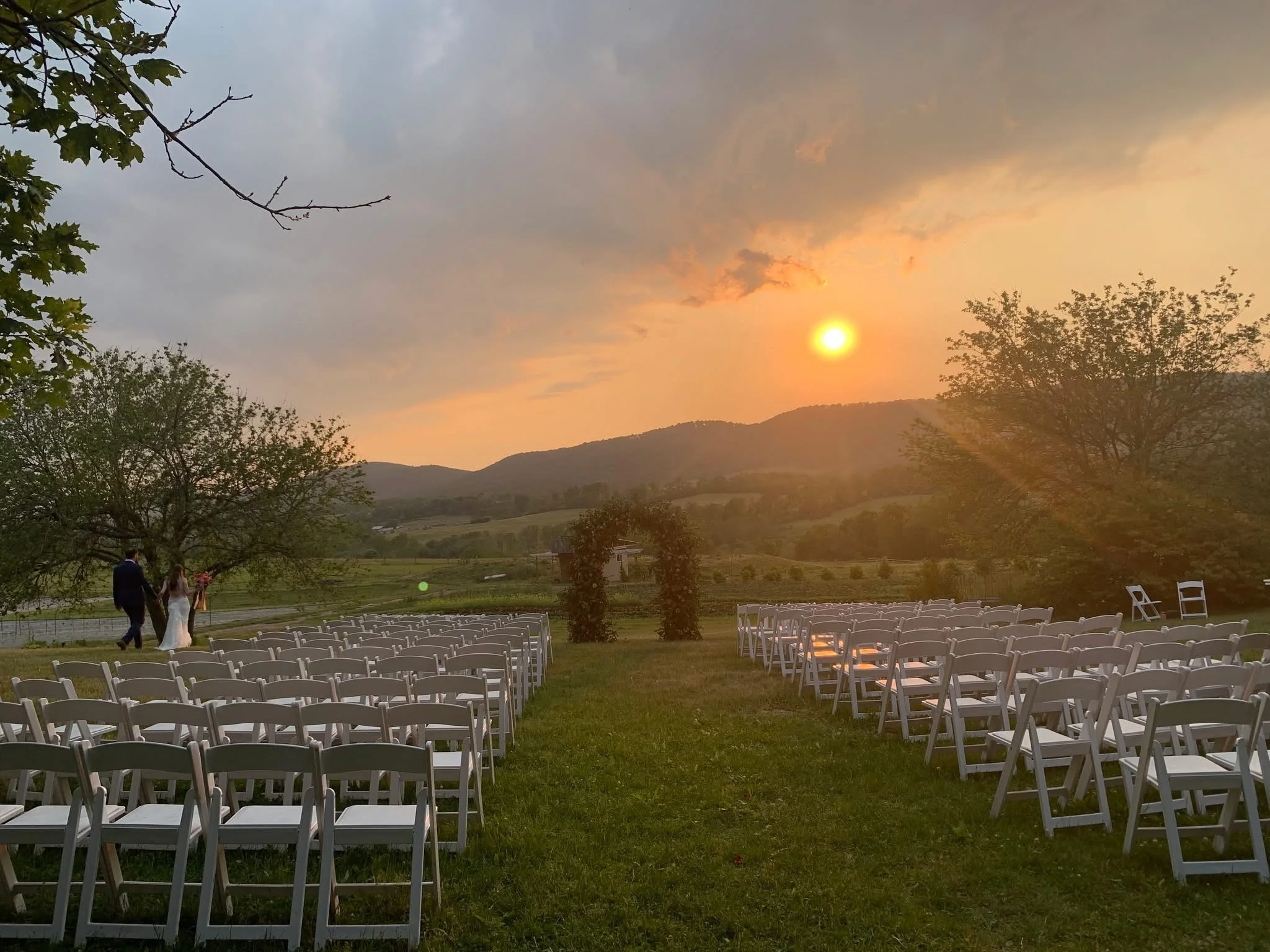 Outdoor wedding ceremony at sunset with chairs and mountains