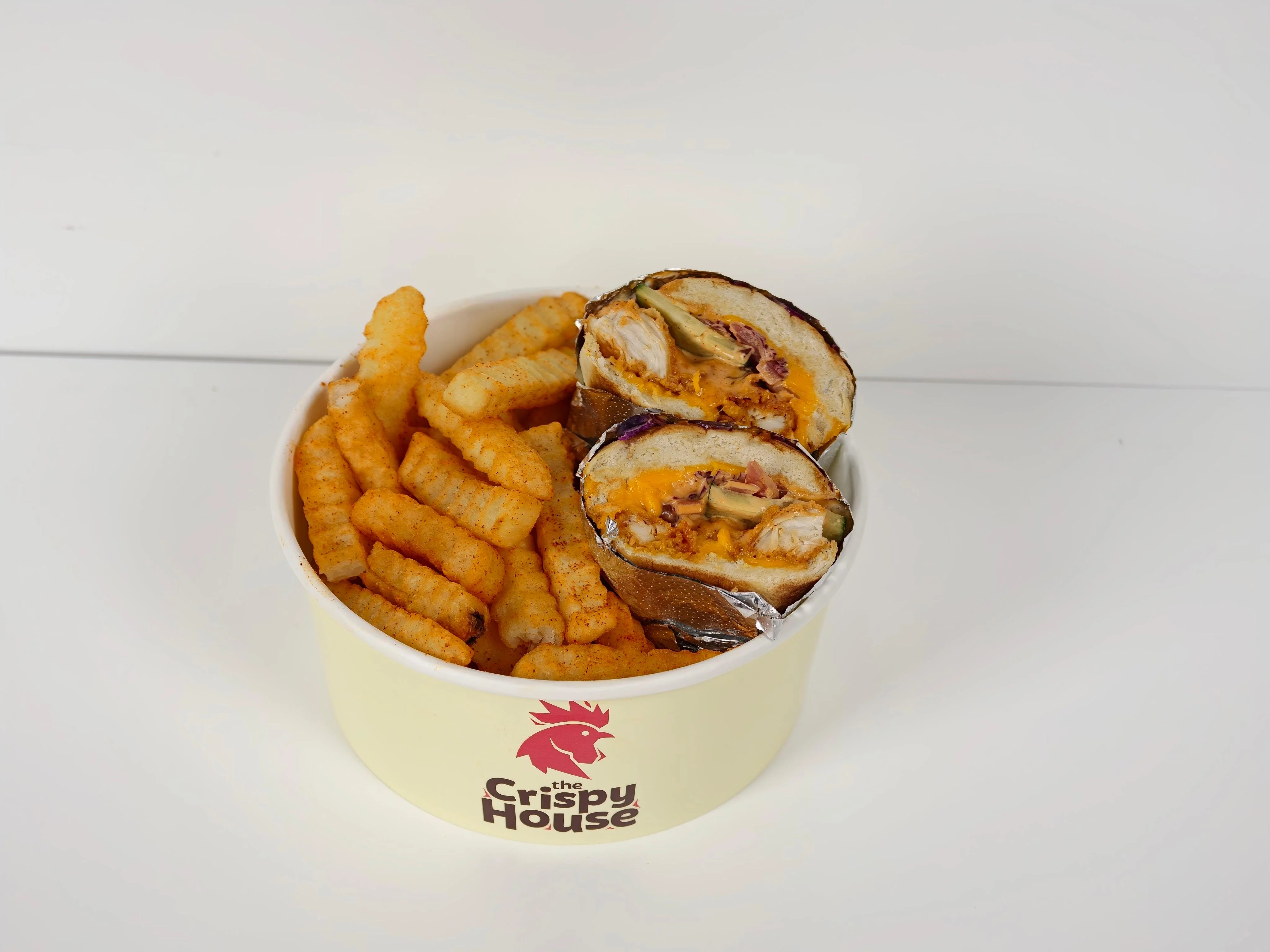 A bowl containing a cut wrap filled with various ingredients, paired with crinkle-cut fries.