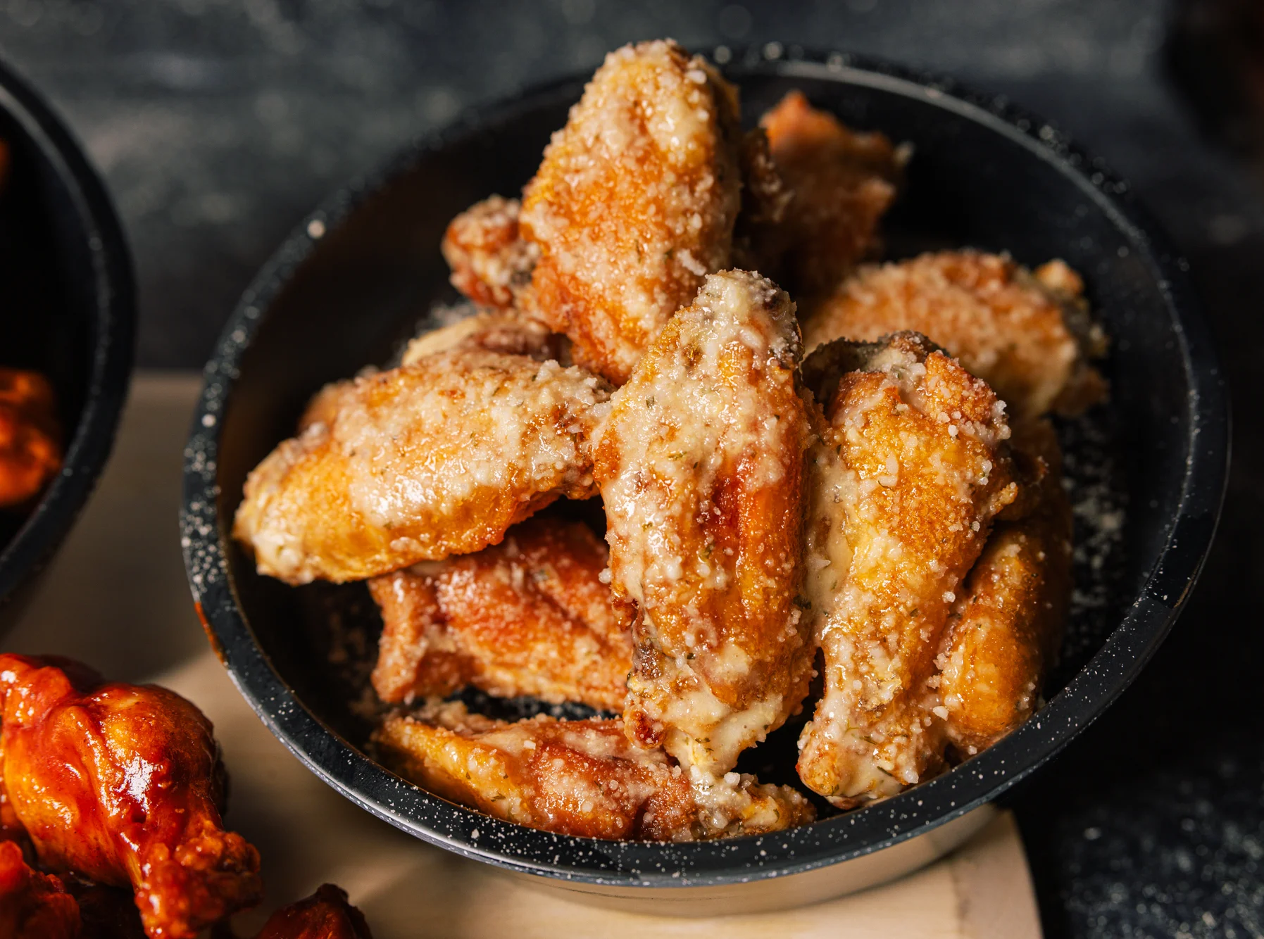 Crispy chicken wings with parmesan coating in a black bowl